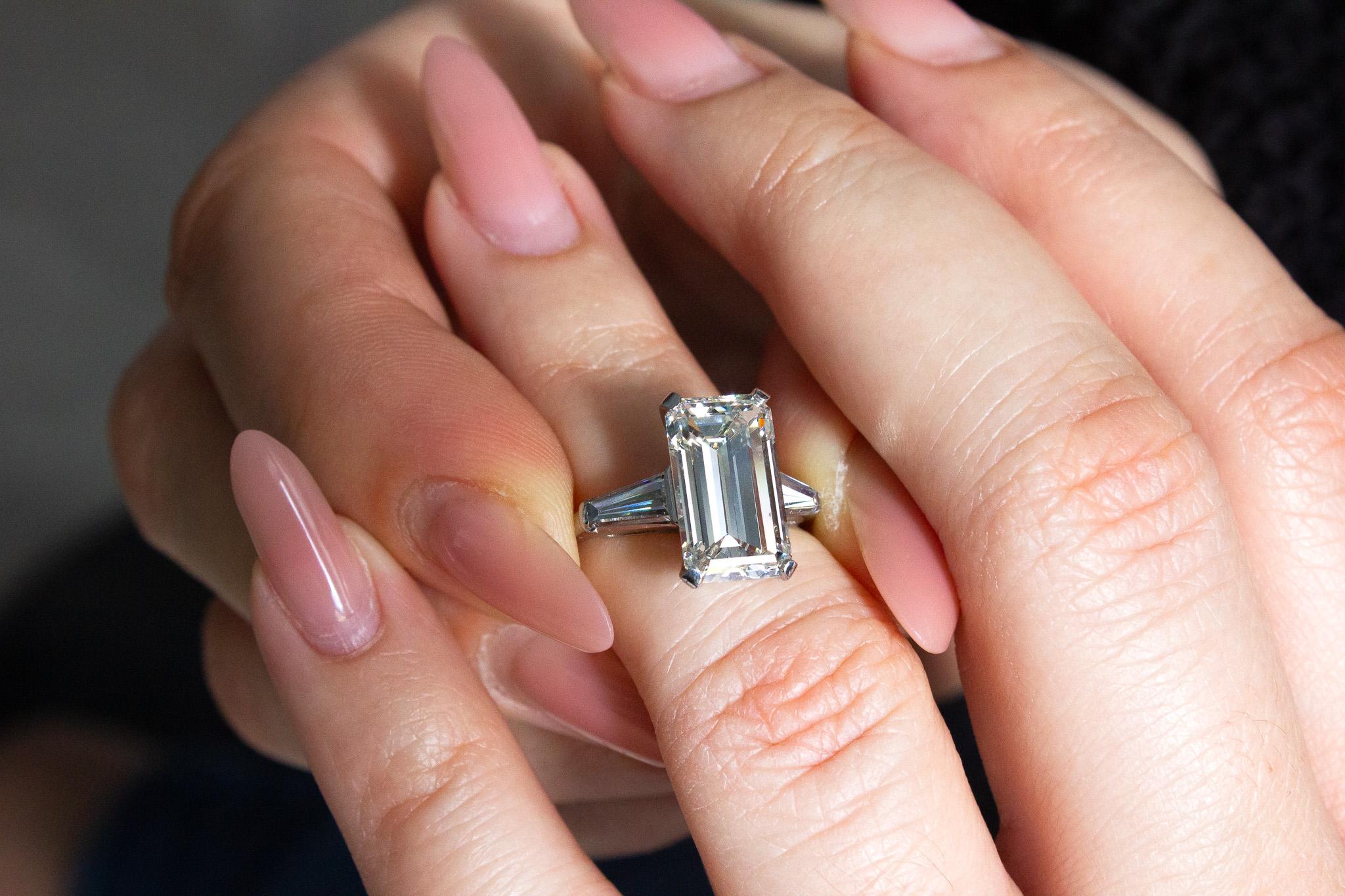 Embrassez la beauté intemporelle avec cette exquise bague à trois pierres en diamant taille émeraude. La pièce maîtresse de cette remarquable bague est un éblouissant diamant taille émeraude de 4,80 carats, de couleur J et de pureté VS2 selon la