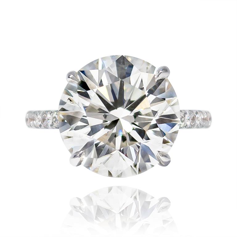 This magnificent ring features a 7.02 carat Brilliant Round diamond of J color and SI2 clarity. Lively and scintillating, this diamond ring is an unbelievably large look for the price point. The handmade, platinum mounting is set with 12 diamonds =