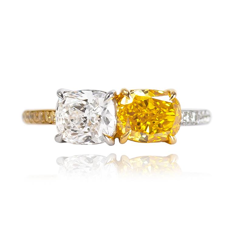 This scintillating, two-tone masterpiece from the J. Birnbach workshop features a breathtaking pair of GIA certified diamonds: a 1.02 ct cushion of G color and VS1 clarity and a 1.09 ct oval of Fancy Vivid Yellow Orange color and VS1 clarity. Set in