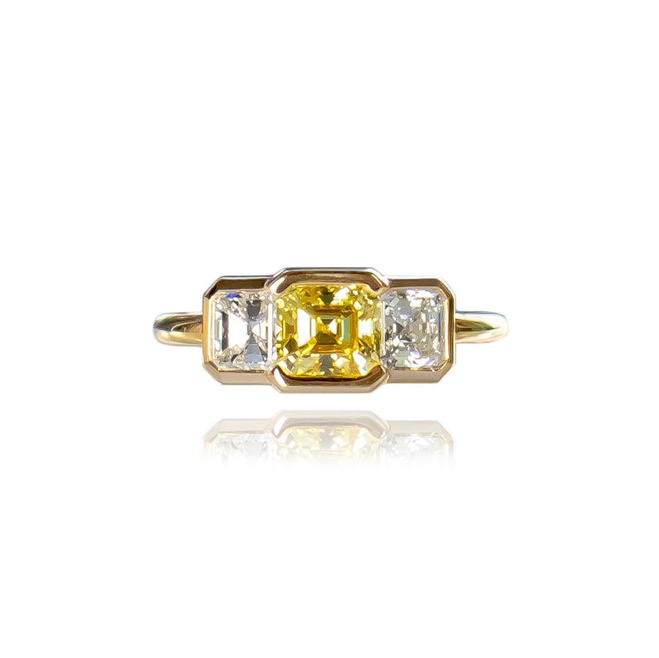 This exceptional execution by the house of J. Birnbach features an exquisite, natural, GIA certified 0.90 carat Emerald cut diamond of Fancy Intense Yellow color and VS1 clarity as described by GIA grading report #2239328047. The center is flanked