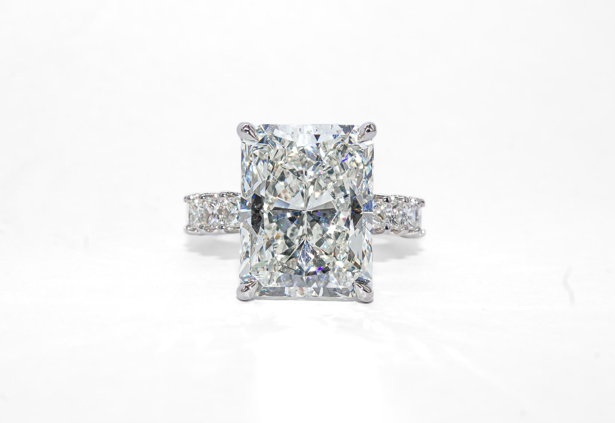 This extraordinary platinum engagement ring from J. Birnbach is a celebration of rarity and thoughtful design. At the center is a spectacular 9.06 carat radiant cut diamond, certified by HRD as I color and SI1 clarity. With its dazzling brilliance