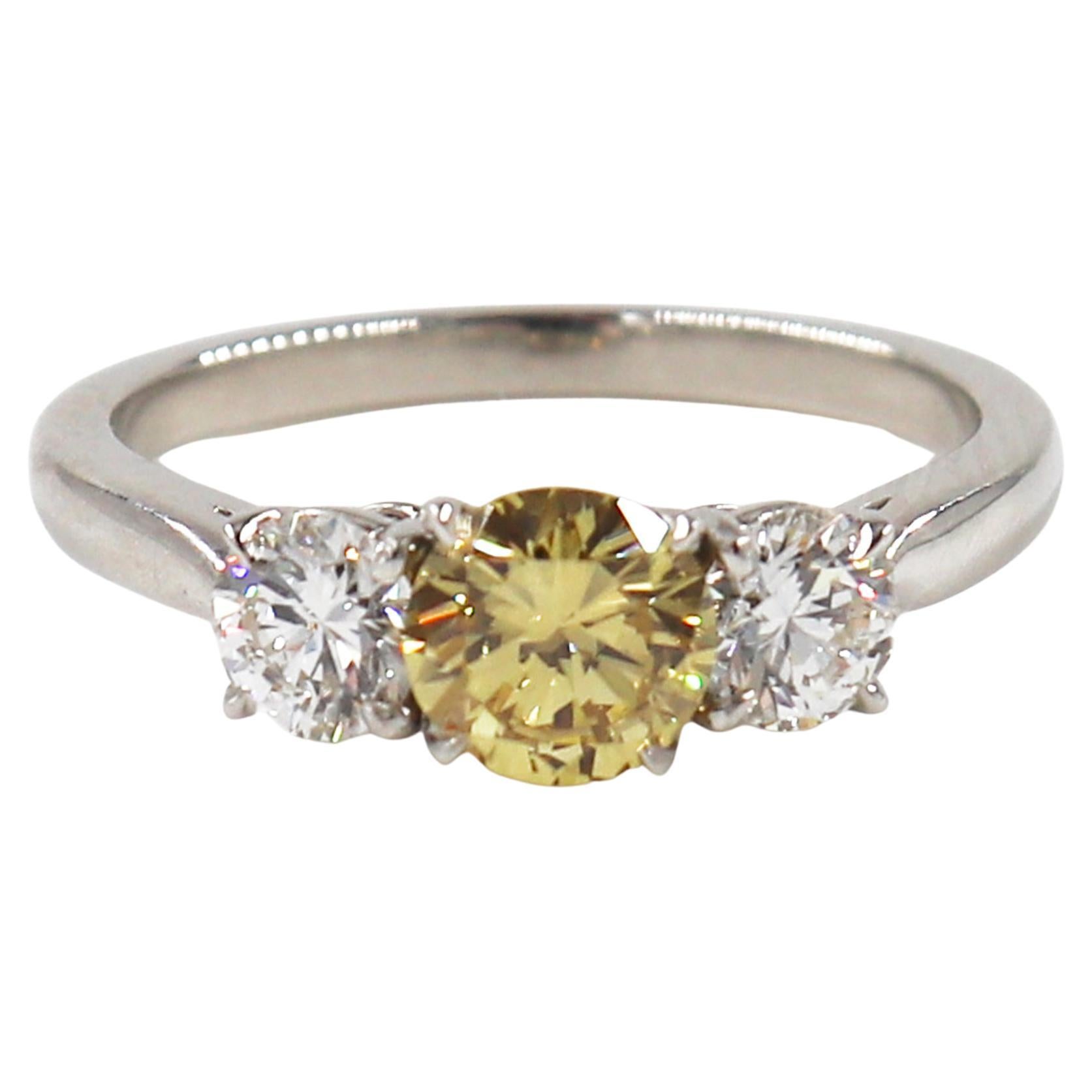 This charming three stone ring by J. Birnbach ring is a unique take on a timeless design. The center diamond is a round 0.66 carat Fancy Intense yellow diamond, and it is accented by two round diamonds, which together are 0.62 carats. The rich,