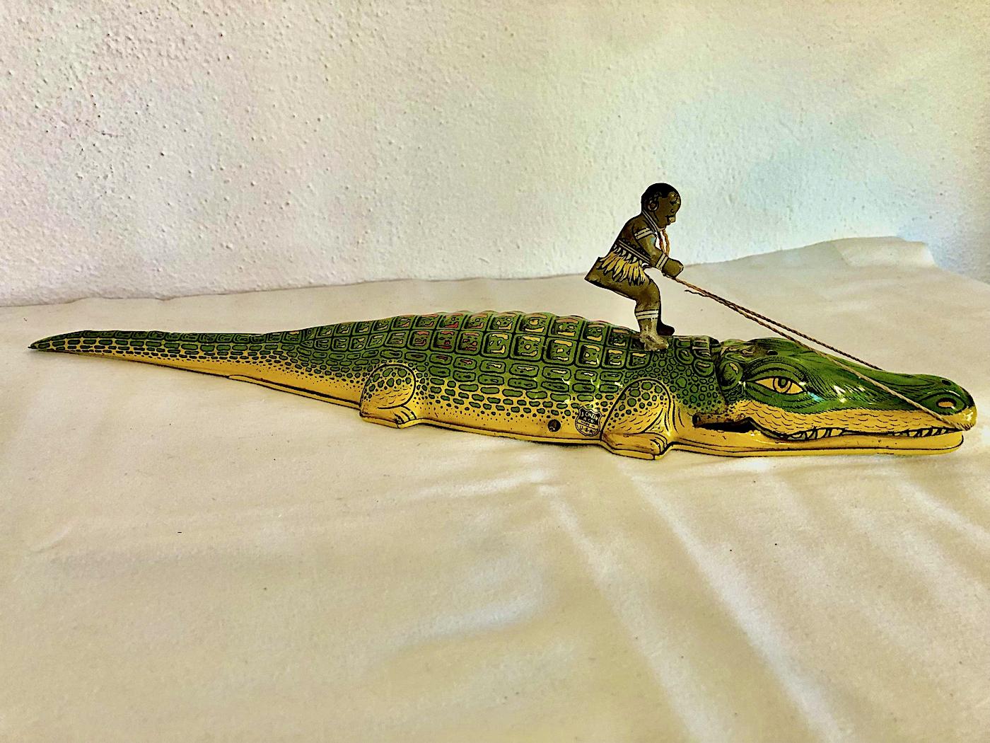 Manufactured in the mid 1930s by J. Chein & Company in Harrison, New Jersey, this vintage wind-up toy depicts a boy riding an alligator. A wound-up clockwork key powers the alligator forward with its mouth opening and closing somewhat menacingly.
