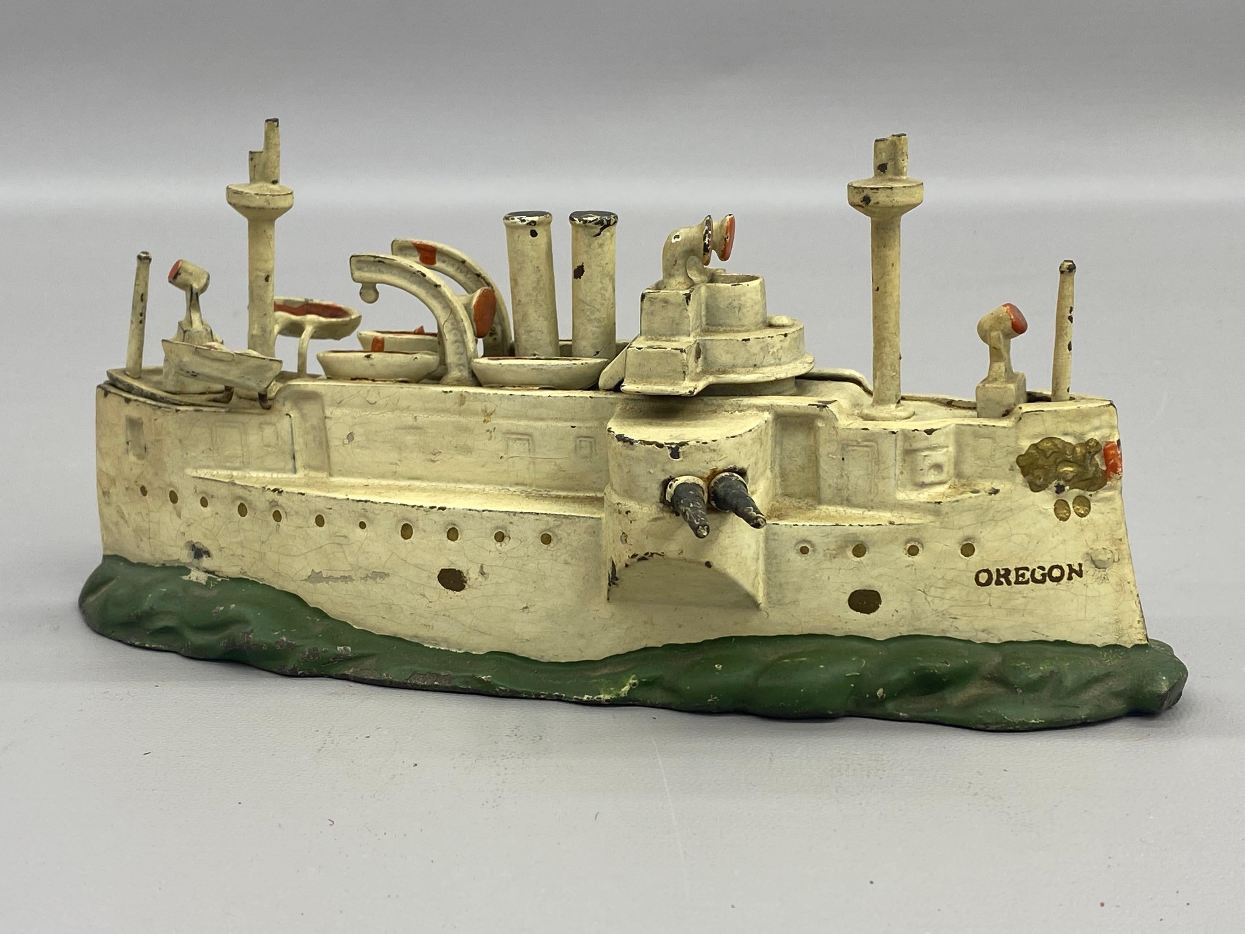 Cast iron USS Oregon battleship still bank. J & E Stevens Company. Circa 1910-20. A slot for coinage and coin removal from the stern. Nicely detailed with lifeboats, conning tower, and gun turrets.

Wikipedia: USS Oregon (BB-3) was the third and