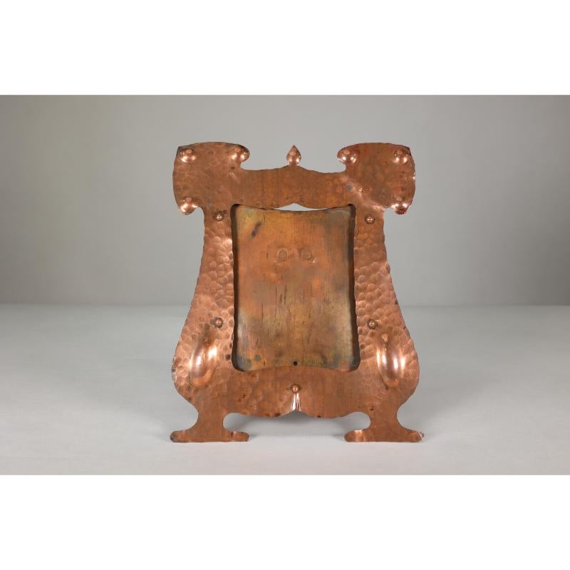 J & F Poole Hayle copperworks in Cornwall. An Arts and Crafts hand-hammered copper picture frame with a writhen stand to the back.
