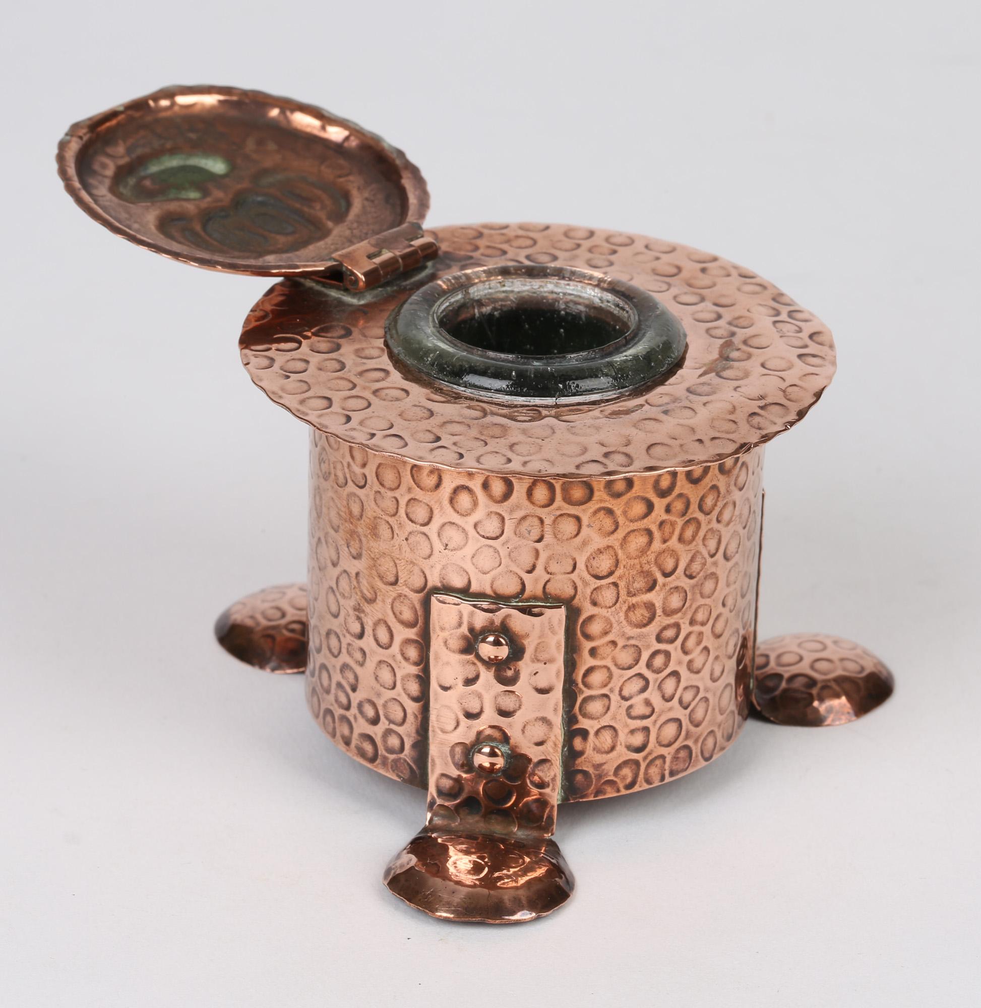 A very stylish Arts & Crafts hand-beaten lidded copper inkwell by J F Poole Hayle dating from around 1895. Made in Cornwall the inkwell is of rounded cylindrical shape and stands raised on three folded flat rounded and domed feet riveted to the