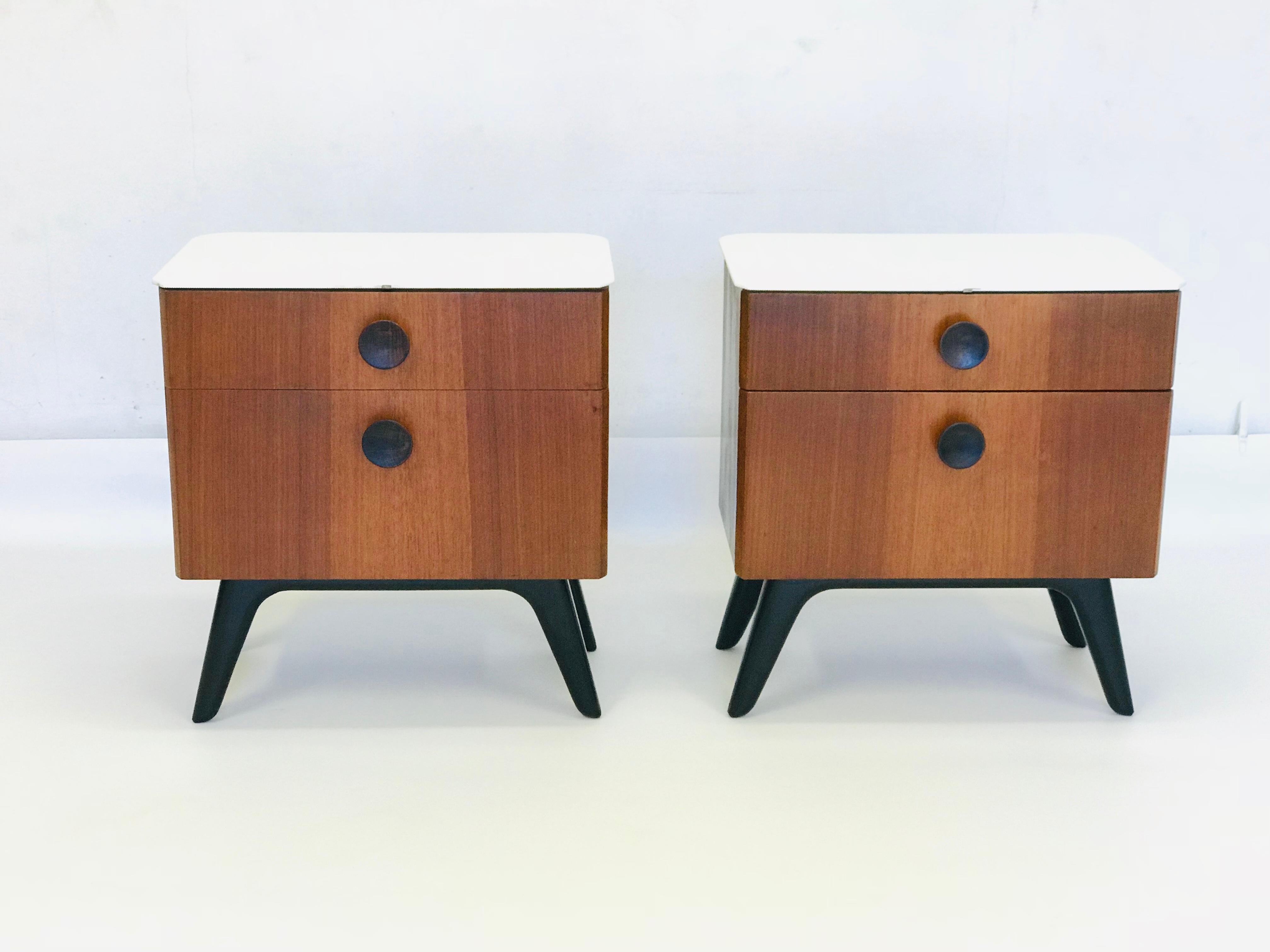 Pair of beside tables are in original condition. They are made by UP Zavody according the design architect J. Halabala. There is a milk glass on the top. The table is made of nut veneer, table legs are black.