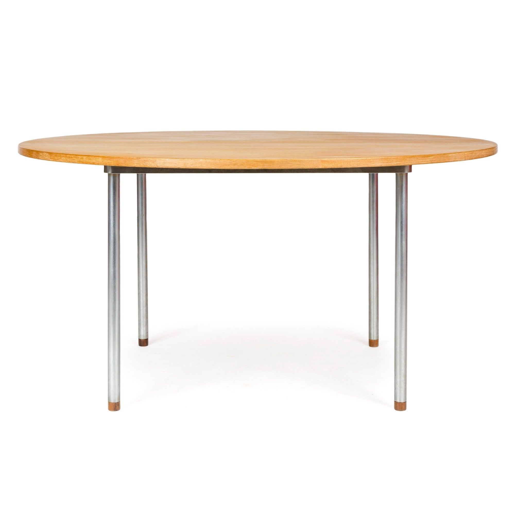 A round extension dining table with oak top set on four tubular chrome legs each tipped with a rosewood insert. Chairs sold separately.