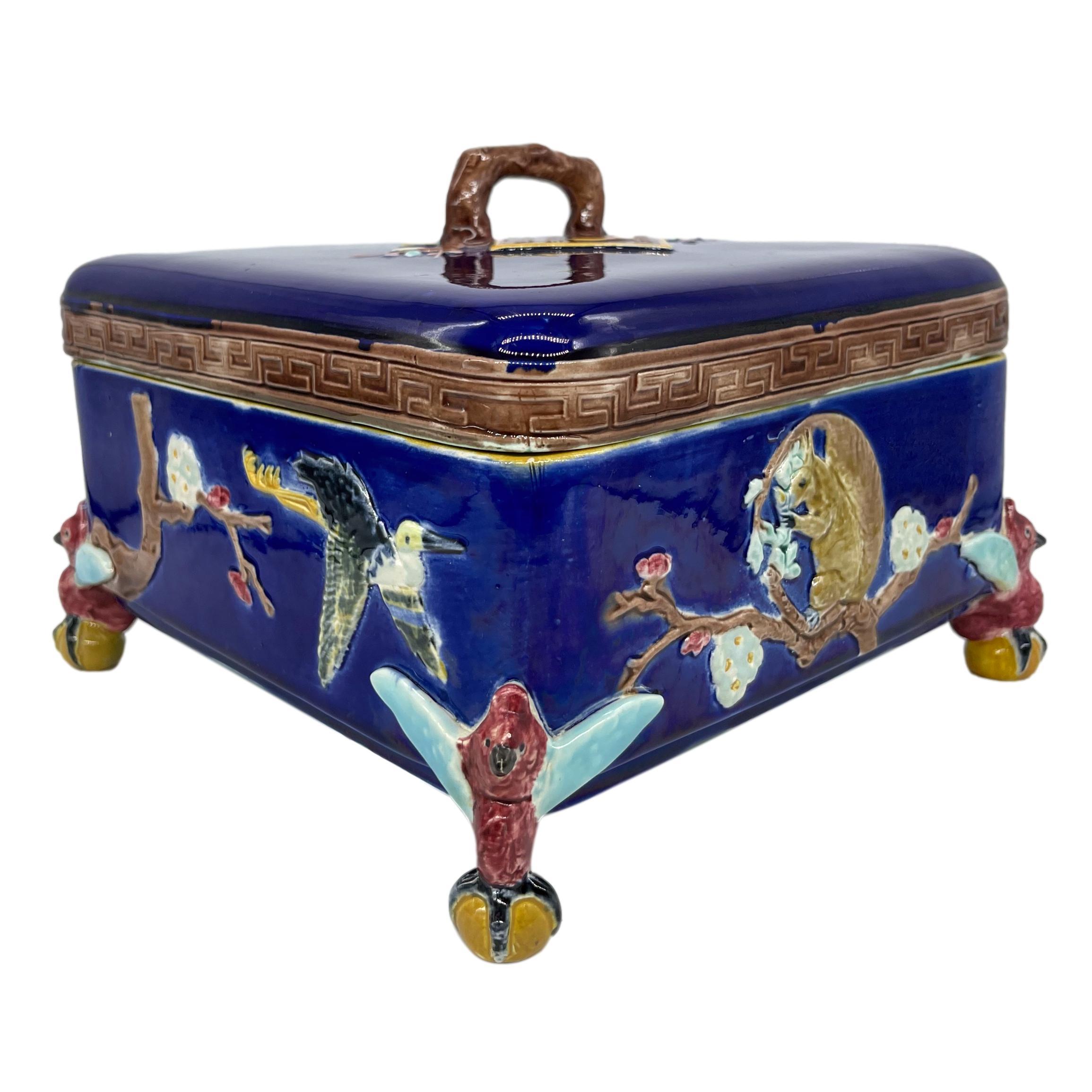 Joseph Holdcroft Majolica Japonisme square shaped box and cover, glazed in cobalt blue, with relief molded flying cranes, flowering prunus branches, and squirrels, the cover bordered with a Greek key design, with a prunus branch handle above two