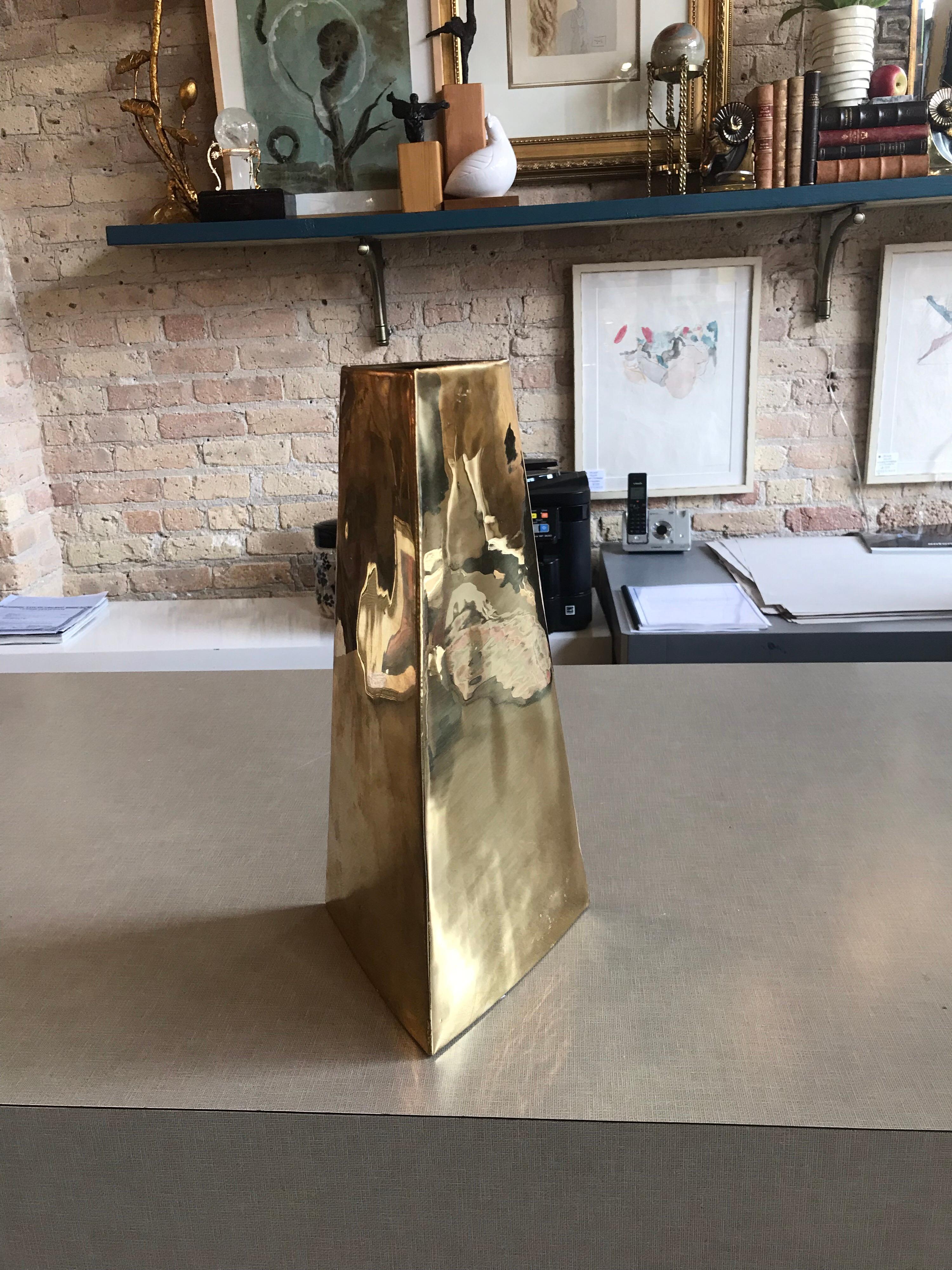 This is a brass triangular shaped tall vase designed by James Johnston and signed on bottom. It has a modern feel that would complement most any room