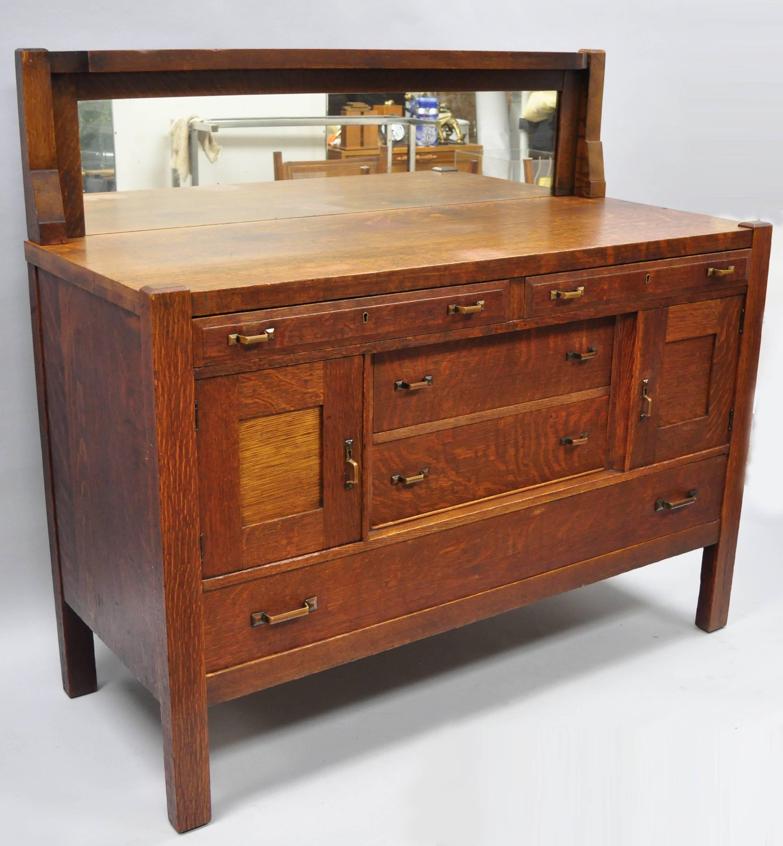 Antique J. K. Rishel Mission Arts & Crafts oak sideboard buffet with mirror. Item features mirrored back splash, copper pulls with beautiful patina, solid wood construction, beautiful wood grain, two swing doors, original label, no key but unlocked,