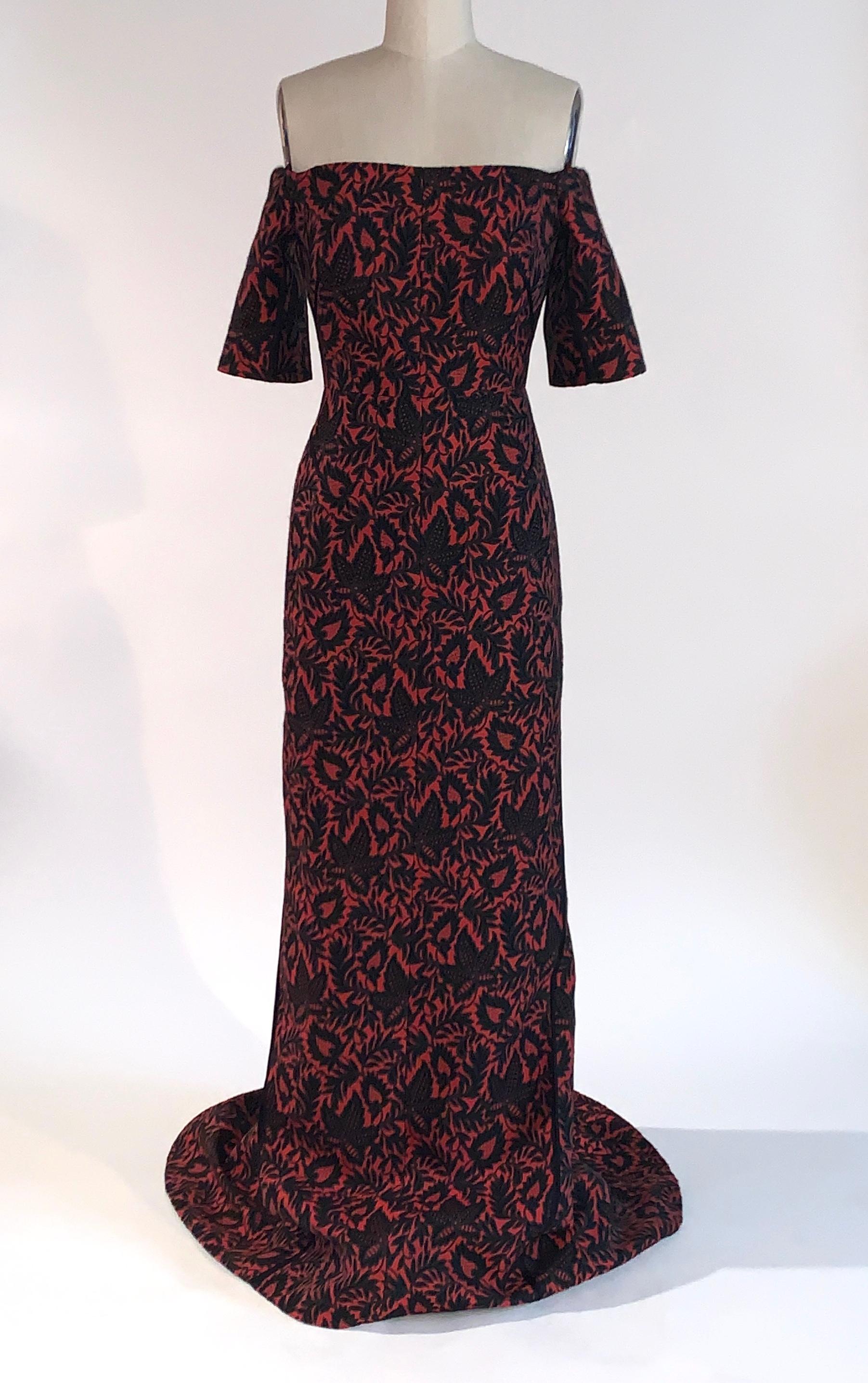 J Mendel red and black leaf print brocade gown. Off the shoulder design with short sleeve. Seams at side and bust feature black trim detail. Slight train at back. Light elastic at shoulders and built in cups at bust. Back zip and hook and eye. 

65%