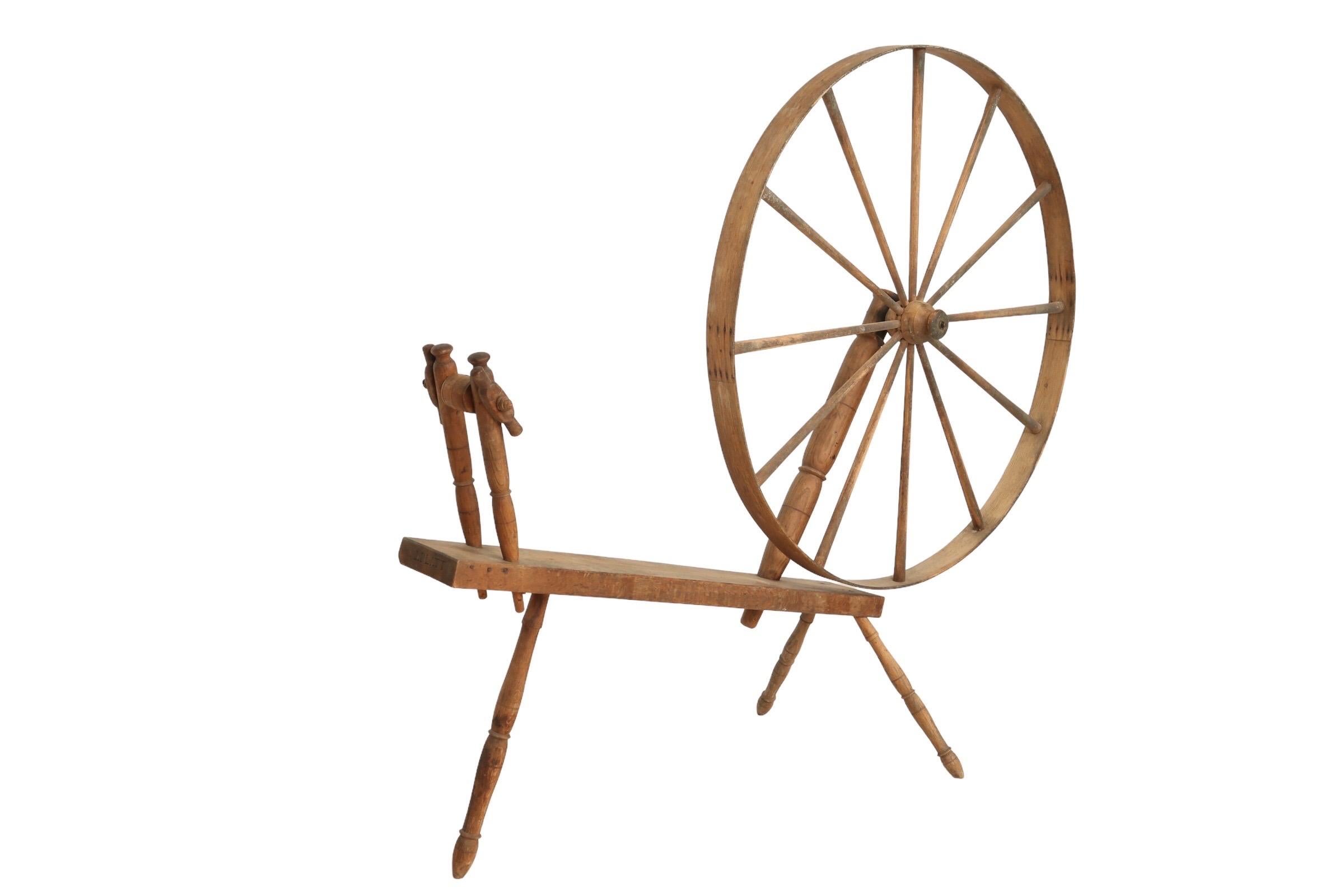 A large wheeled walking spinning wheel designed to be operated while standing, also known as a Great Wheel. Made by J.Platt, as marked on the end of the oak base or table, who made wheels in the late 1700’s and early 1800’s. Three turned pointed