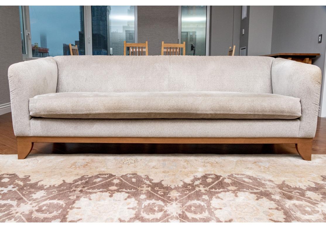 Gut konstruiertes, gepolstertes Einzelsofa, das auf einem honigtönigen Holzrahmen mit kurzen Säbelbeinen ruht. Das Sofa ist mit einem mehrfarbigen, hafergrünen Stoff mit weichem, kurzem Schlingenflor bezogen. Die Arme sind in einem Stück von oben