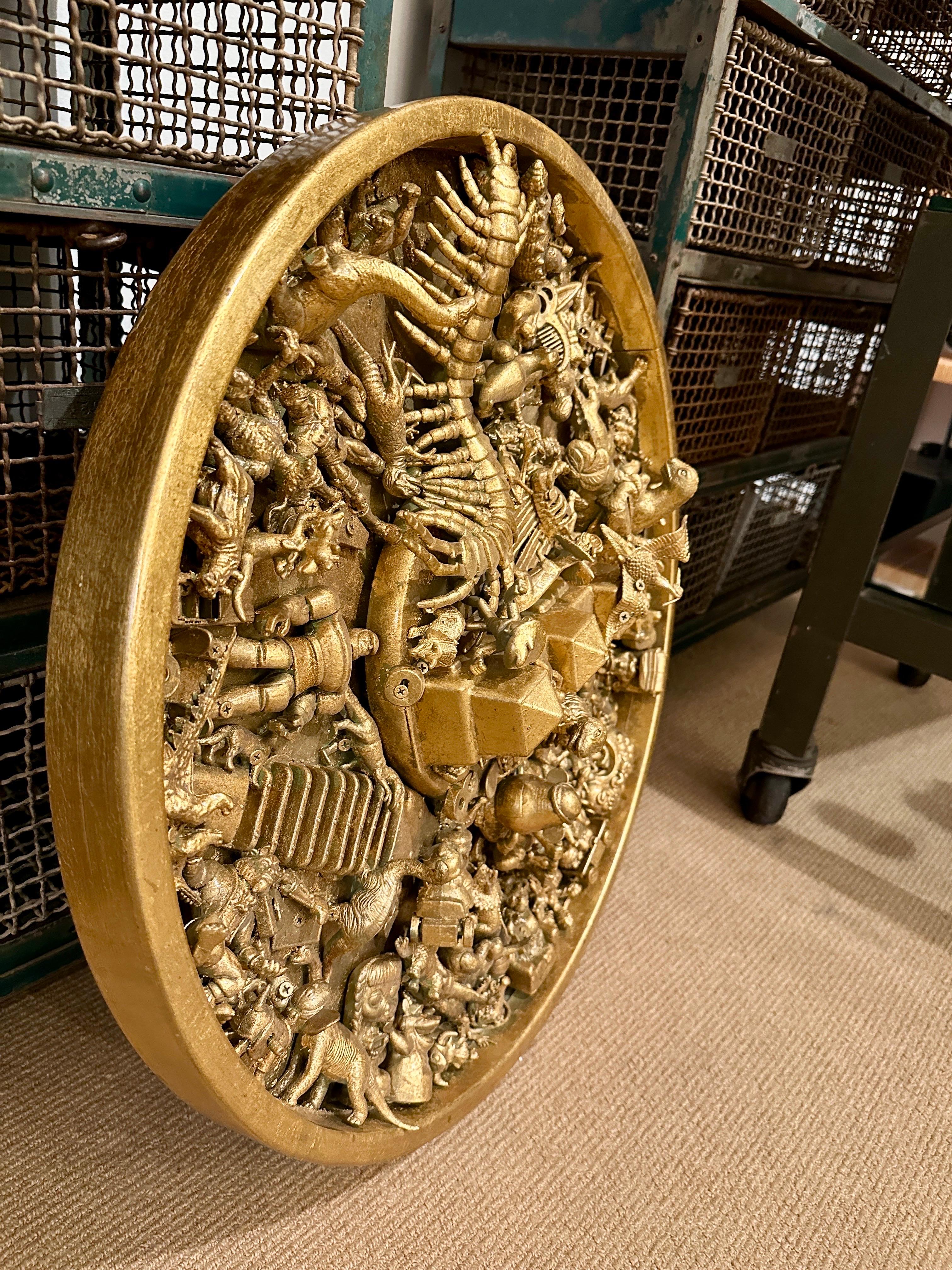 Si tratta di una pesante scultura da parete rotonda dorata in oro e riempita con varie figurine giocattolo.  Anche questa è arte stravagante e bellissima.
