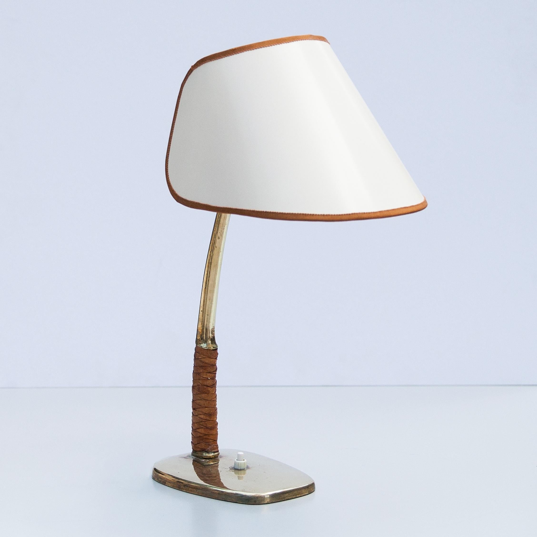 Austrian mid century brass desk / table lamp lamp. 
Designed and manufactured by J. T. Kalmar Vienna in the 1950s as model no. 1191, name is Arnold.

It features a brass base and stem with leather grip and a original crème white shade in