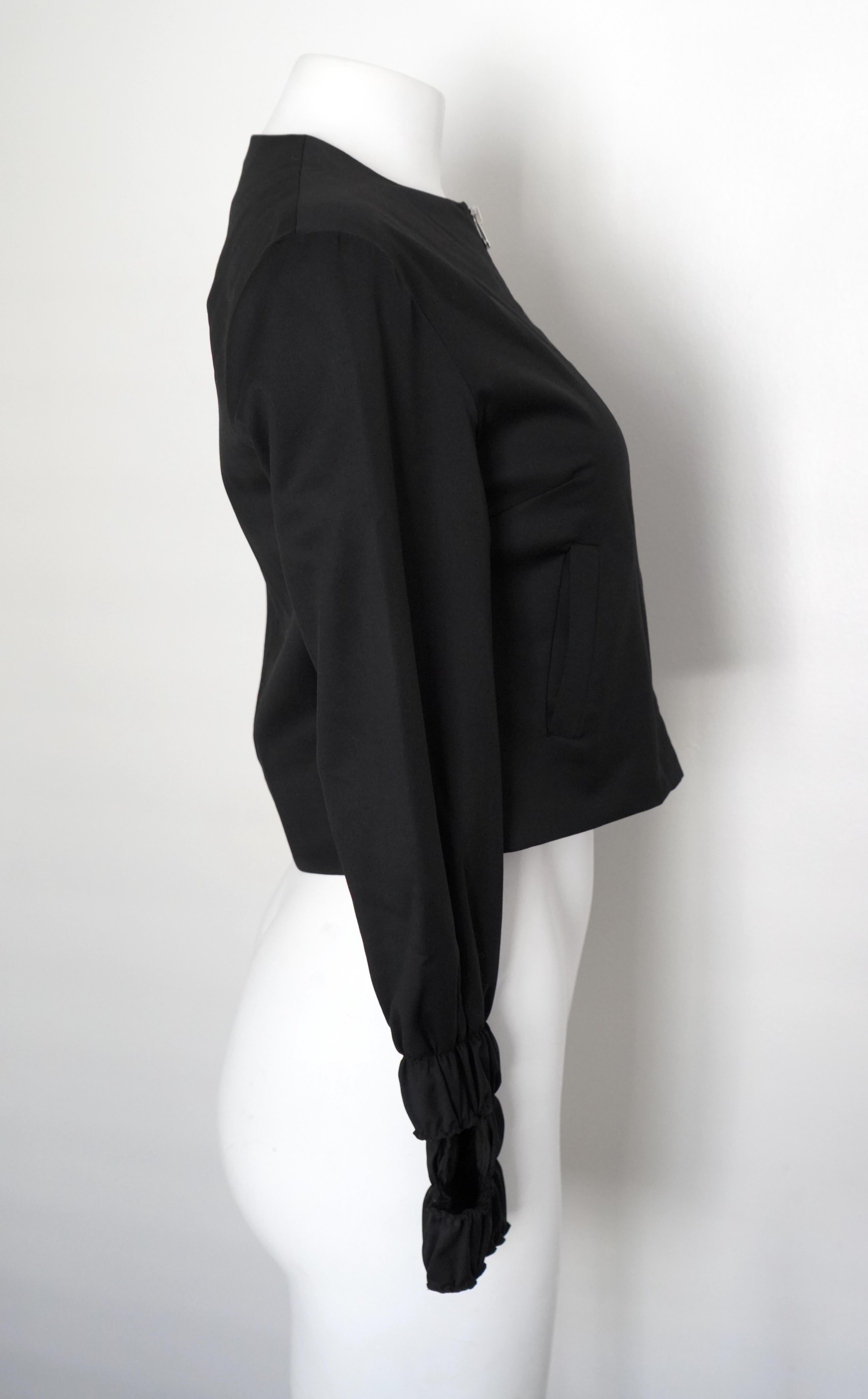 This J. W. Anderson Black Wool Cropped Zip Bolero Jacket in size X-small (UK 6, US 2, Eur 34) combines fashion-forward design with functional elements. With a cropped fit, the jacket showcases pleated sleeves at the wrist, featuring thumb holes for