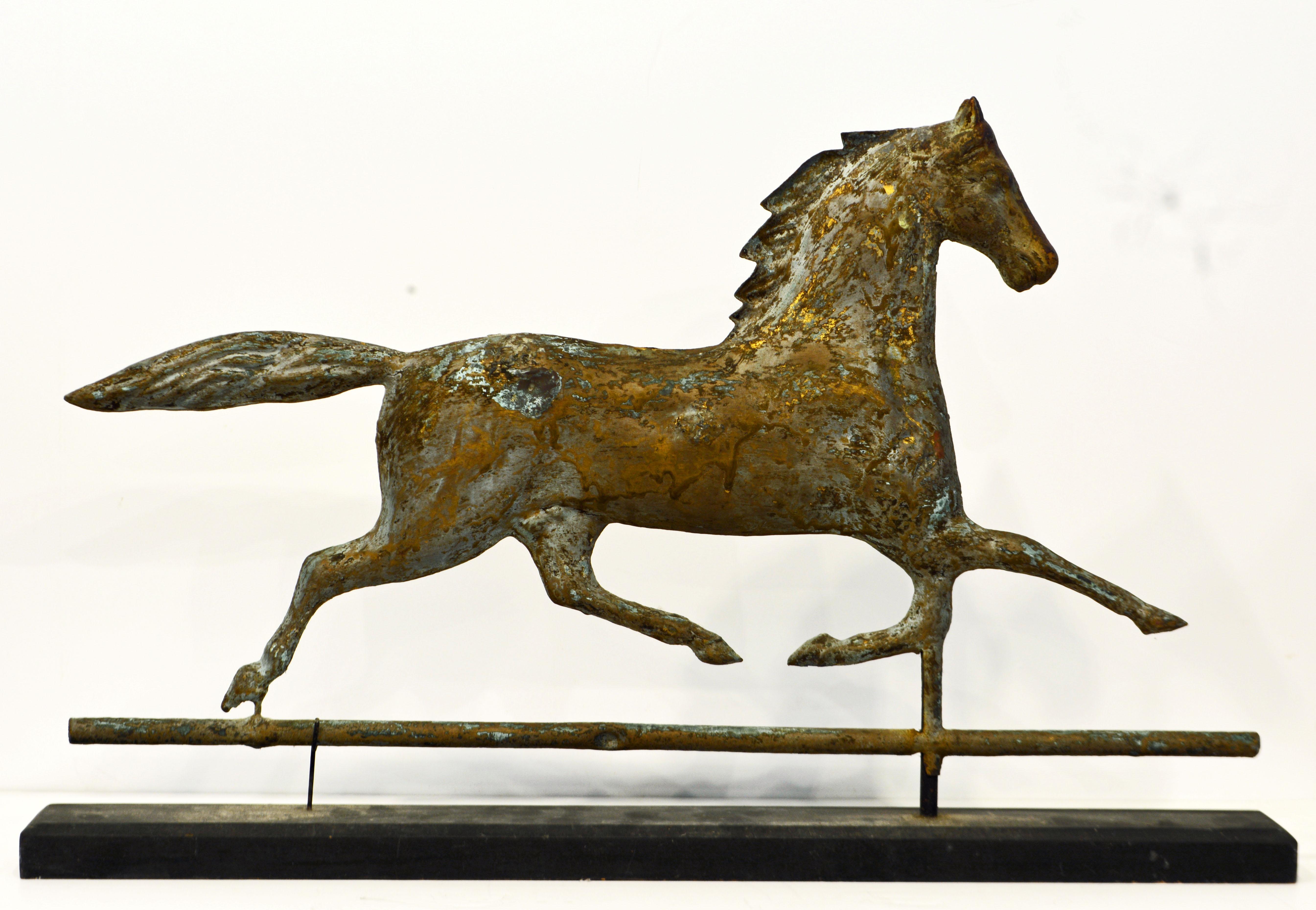 Being 26 in. long this copper weather vane which is attributed to J. W. Fiske & Company features a full bodied carriage horse with a wonderful patina revealing verdigris, traces of gilt and oxidation. The horse is mounted on a long ebonized wooden