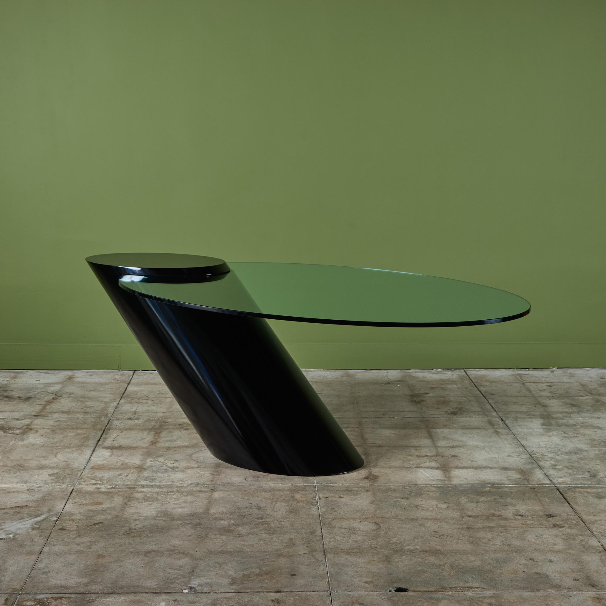 A cantilevered dining table designed by J. Wade Beam for Brueton of New York. This example is typical of Beam's sharp, gravity-defying designs. A steeply angled black enameled tubular base holds a thick slab of glass, balancing the oval tabletop