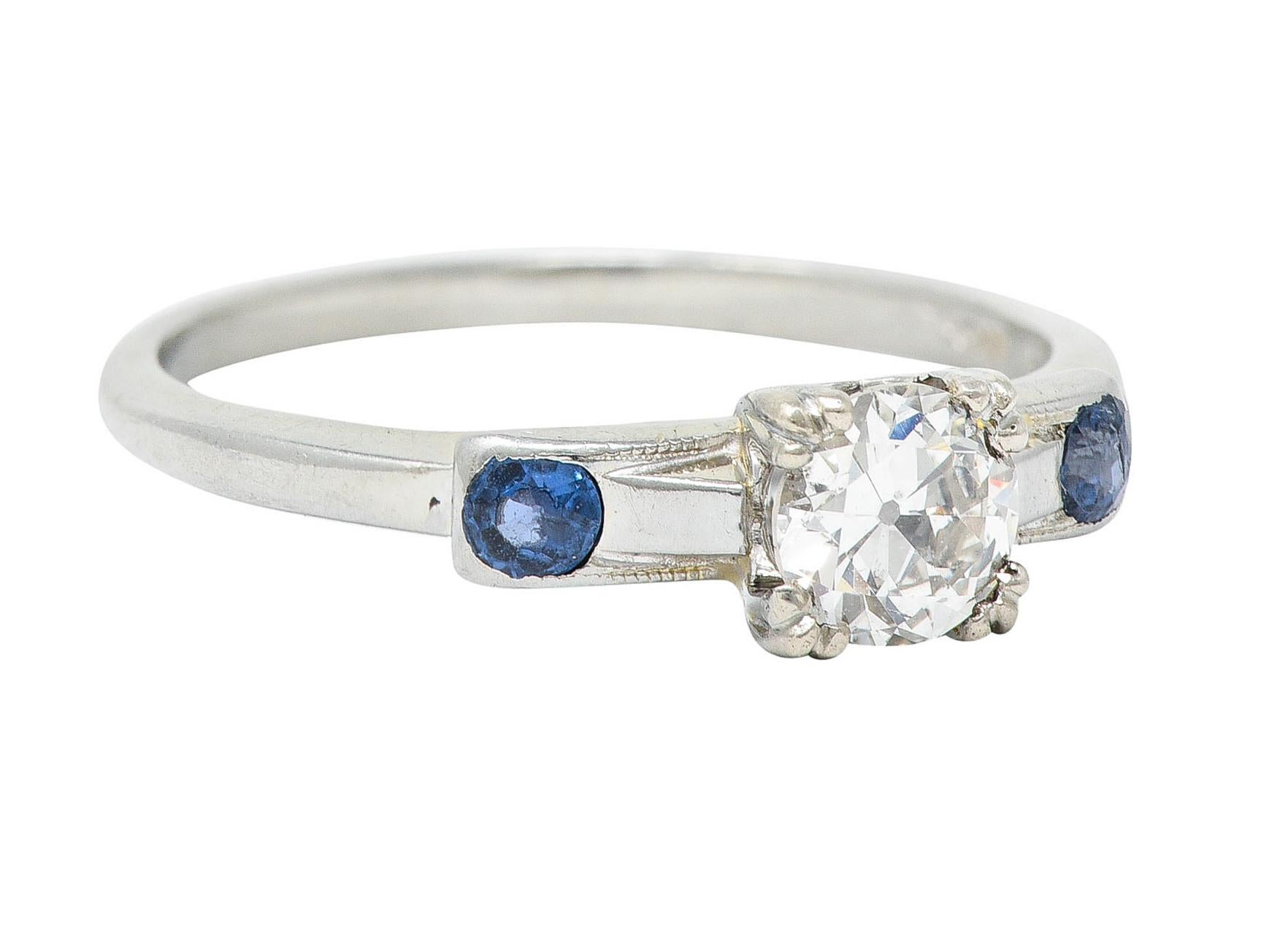 Centering an old European cut diamond weighing approximately 0.43 carat - I color with SI1 clarity

Set by tri-bead prongs in a stylized head

Flanked by rectangular forms accented by round cut sapphires

Cornflower blue in color while weighing in