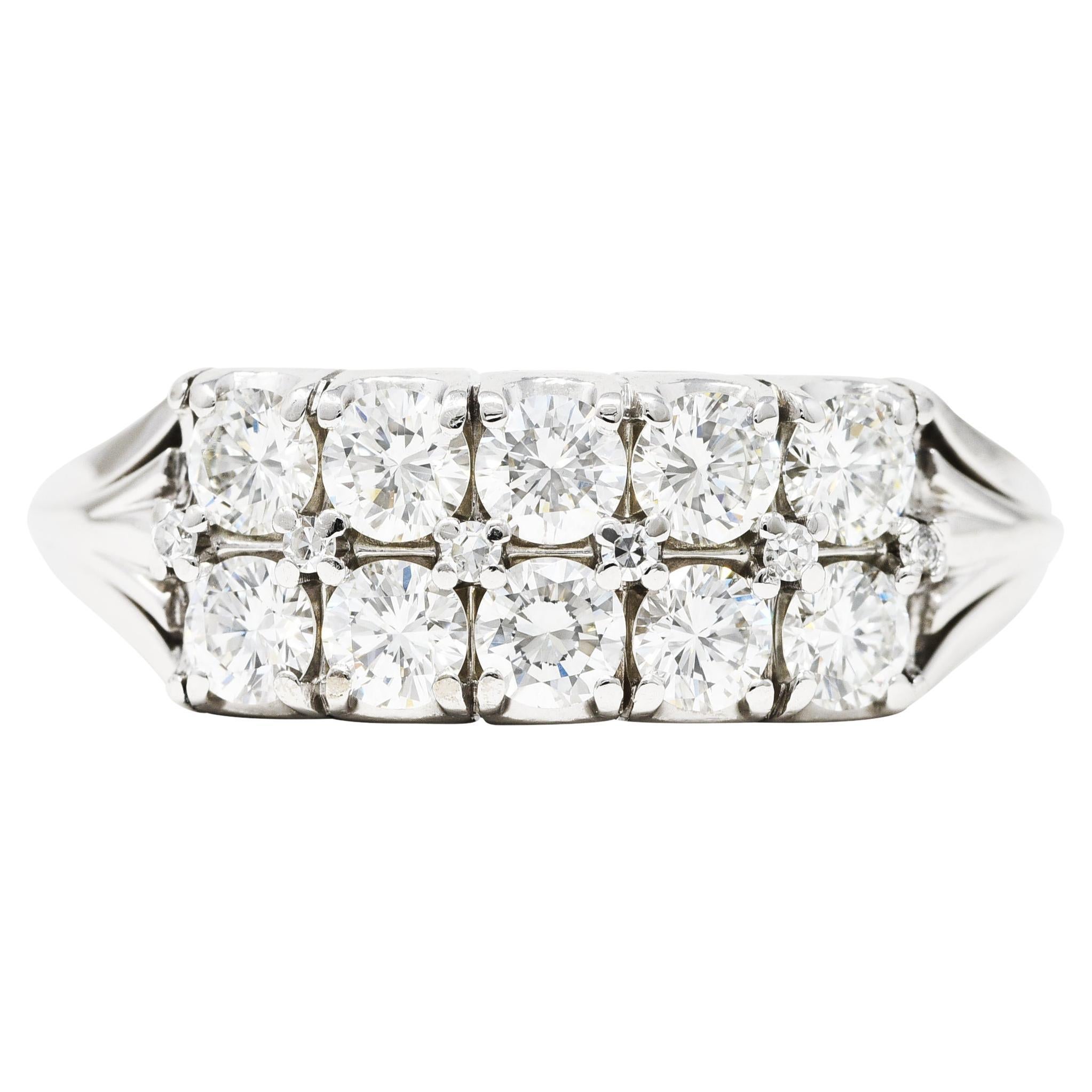 Band ring is designed as two rows of round brilliant cut diamonds. Weighing in total approximately. 1.00 carat - G/H color with overall VS clarity. Basket set East to West and completed by stylized pierced shoulders. Stamped 18K for 18 karat gold.