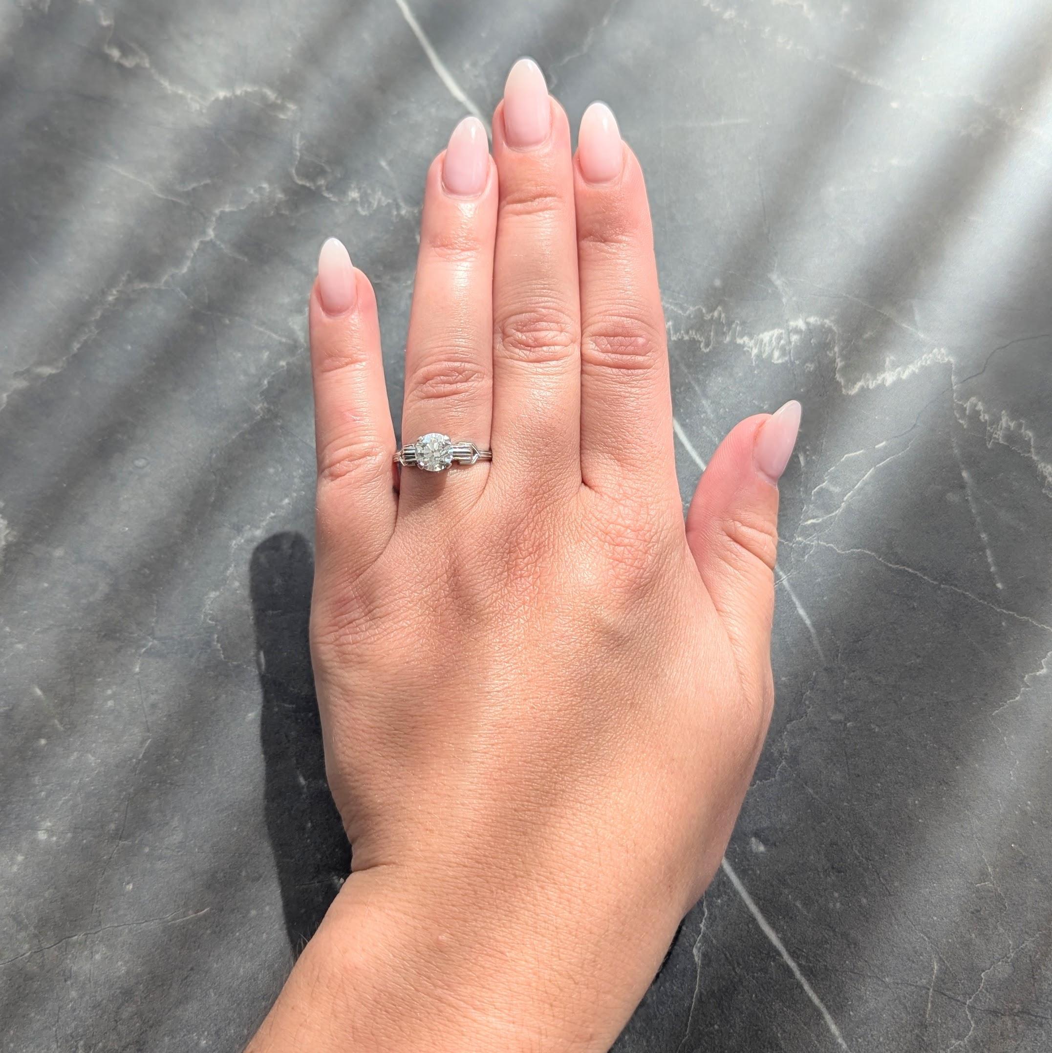 Centré sur un diamant de taille transitionnelle pesant 1,36 carats au total - couleur K et pureté VS2
Les épaules sont serties et flanquées d'un motif de boucle percée.
Avec une tige rainurée et des grains de milgrain sur toute la longueur.
Whiting