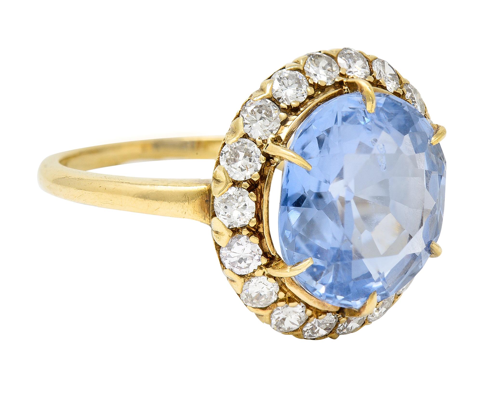 Centering a round cut sapphire weighing 6.27 carats - transparent light blue in color 
Natural Sri Lankan in origin with no indications of heat treatment 
Set with talon prongs with a halo surround of transitional cut diamonds 
Weighing