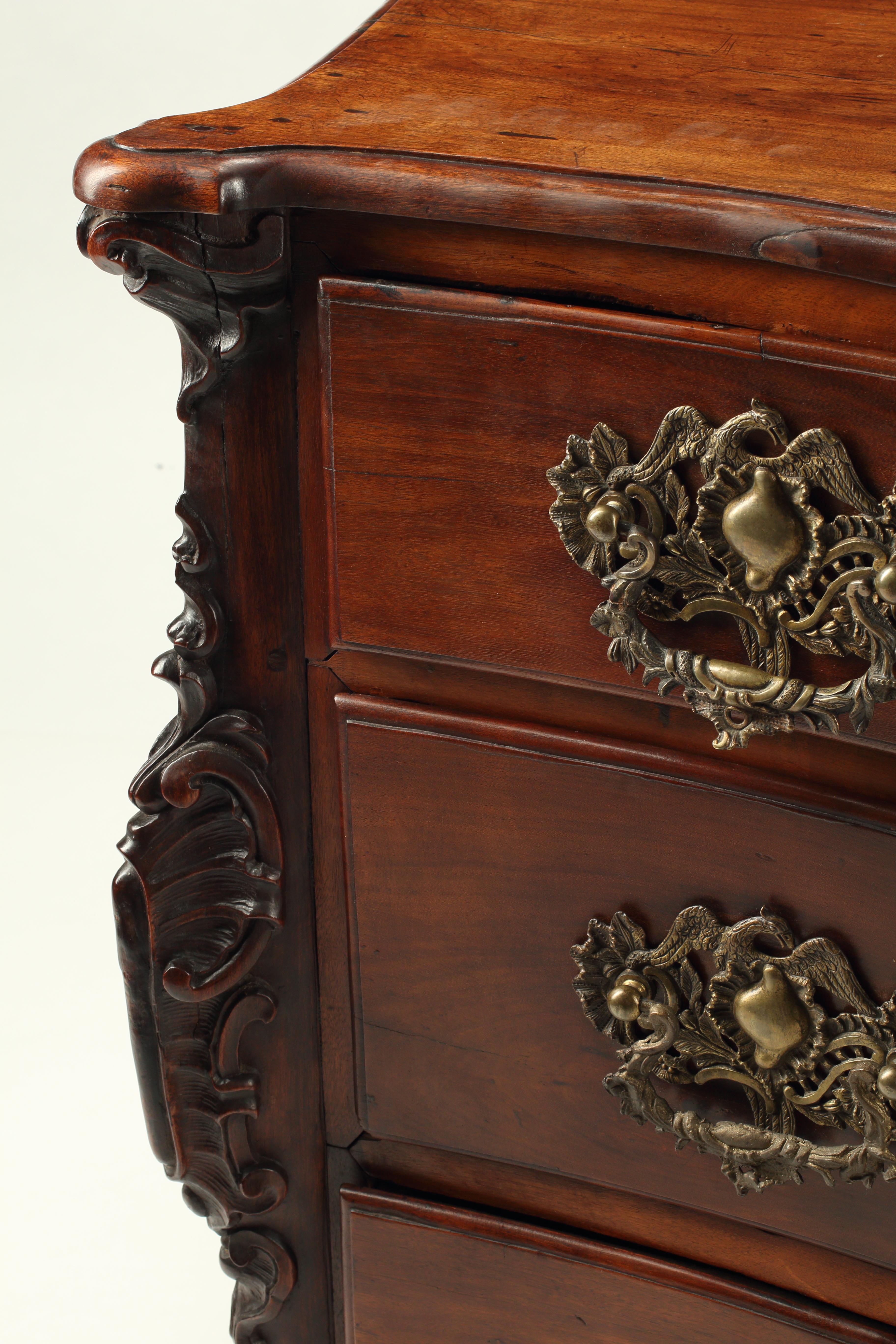 Superba cassettiera portoghese del XVIII secolo in jacaranda con tre grandi cassetti. Le maniglie in bronzo fuse a mano e le serrature raffigurano uccelli, forse fenici, circondati da intricati disegni floreali. Le gonne a ruota mostrano conchiglie