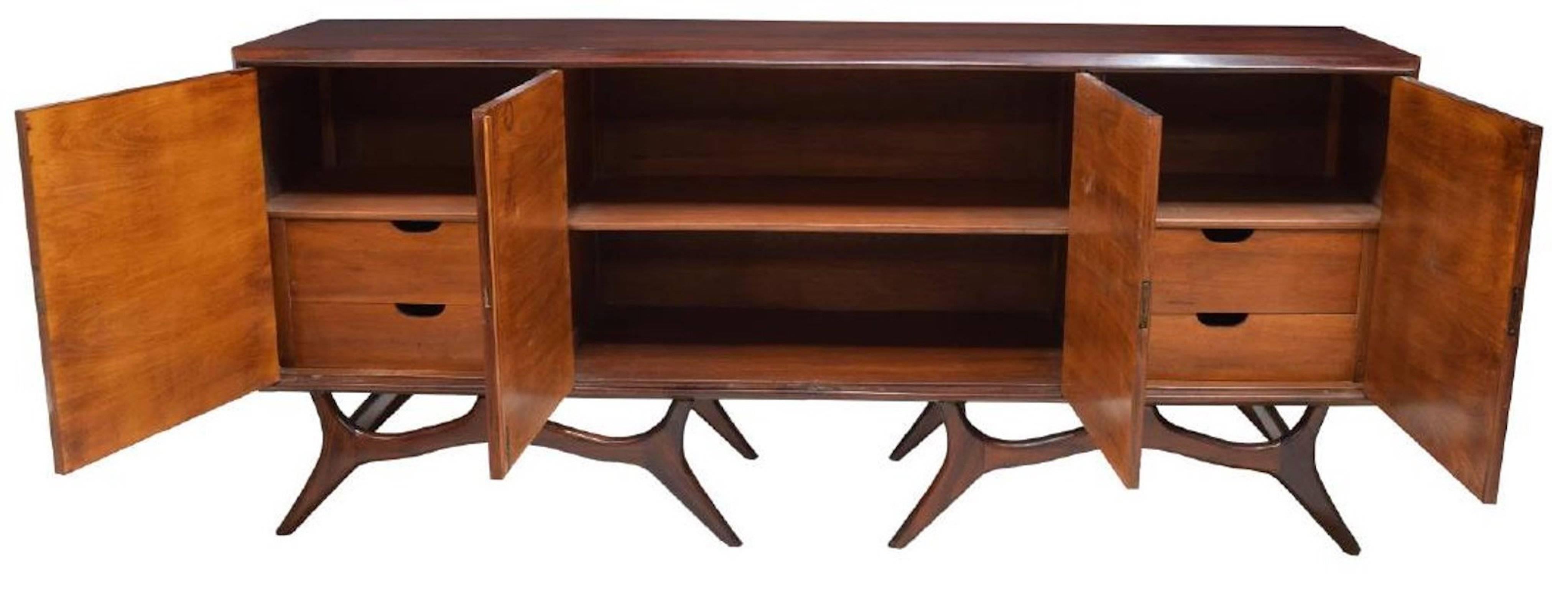 Mid-Century Modern Brazilian rosewood four-door sideboard, circa 1960, with long rectangular case fitted with four cabinets, centre double-door cabinet opening to shelves, flanked by side cabinets with two interior drawers each, rising on two sets