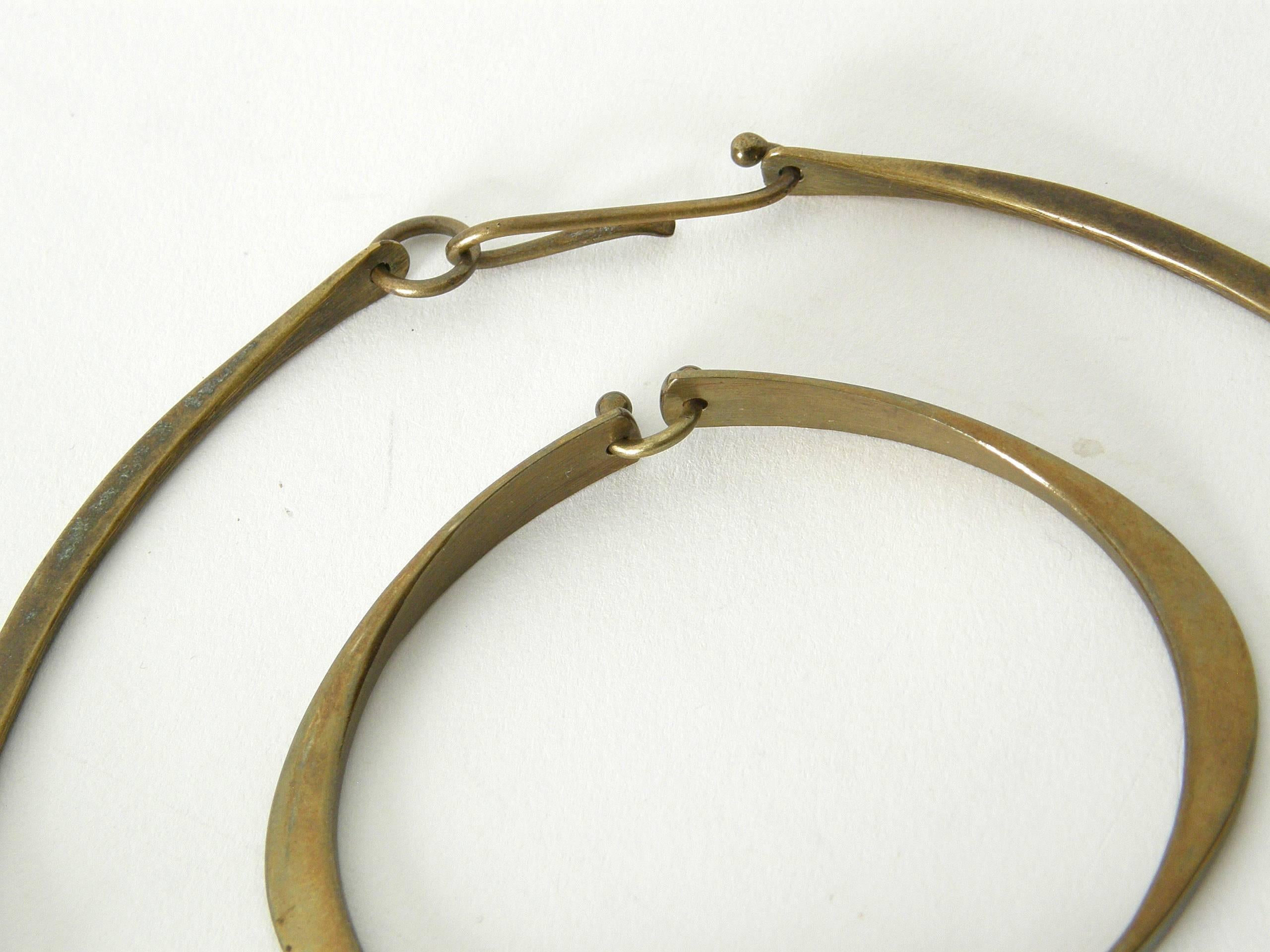 This hand wrought, sculptural bronze set attributed to Jack Boyd combines an organic modern simplicity with a hint of brutalism. The elegantly curved sections of the neck ring and bracelet are joined by playful wire links. The pendant features a