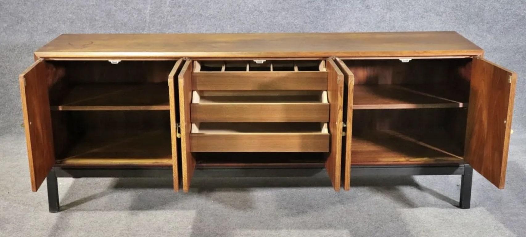 Long walnut sideboard by Jack Cartwright for Founders Furniture. Three cabinets with shelving and drawer storage.
Please confirm location NY or NJ
