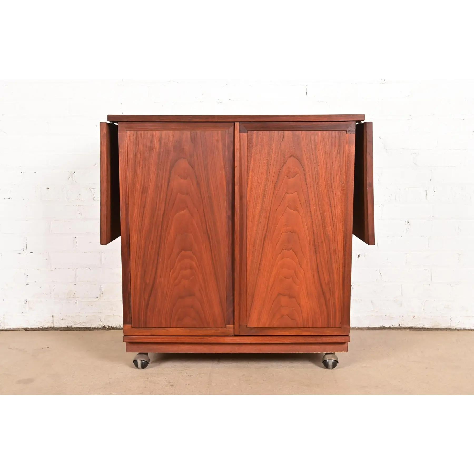 A sleek and stylish Mid-Century Modern rolling extending bar cart or buffet server cabinet

By Jack Cartwright for Founders

USA, 1960s

Sculpted walnut, with durable laminate top.

Measures: 34.5