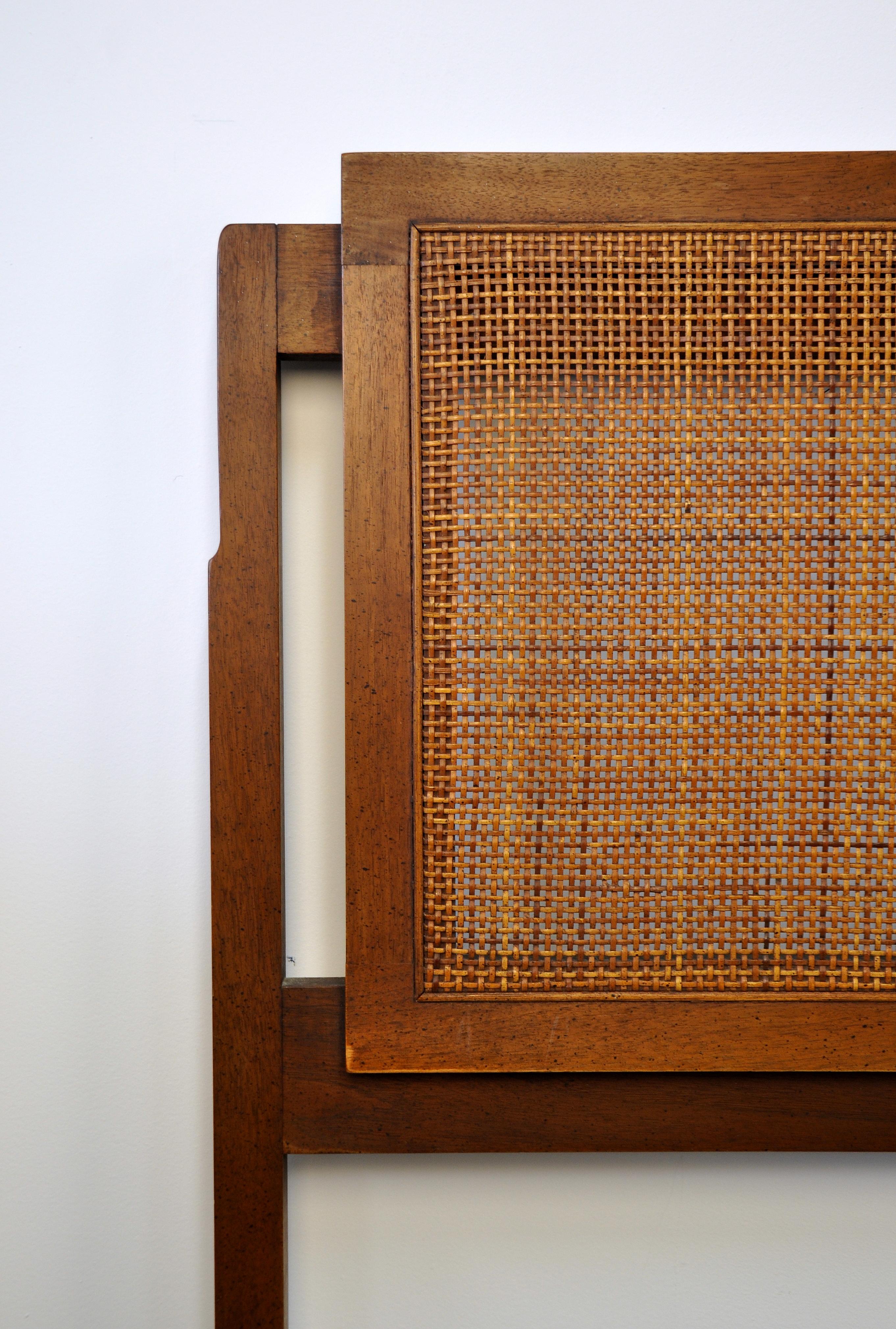 A vintage Mid-Century Modern king size walnut bed designed by Jack Cartwright and manufactured by Founders Furniture in the 1960s. The bed frame features caned panels and a solid walnut frame.