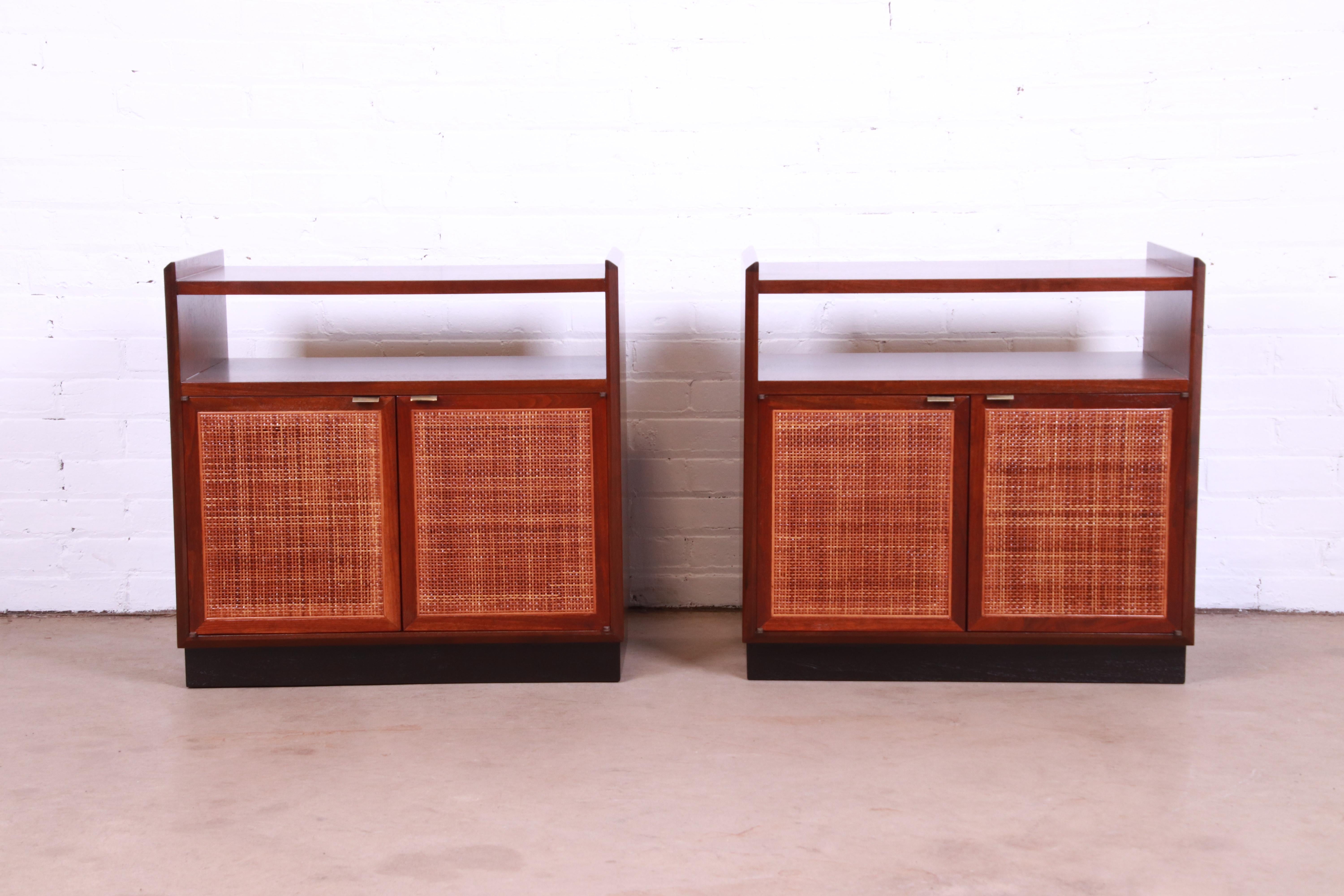 A gorgeous pair of mid-century cabinets or nightstands

By Jack Cartwright for Founders

USA, 1960s

Walnut, with woven rattan door fronts, black lacquered plinth base, and original brass hardware.

Measures: 26