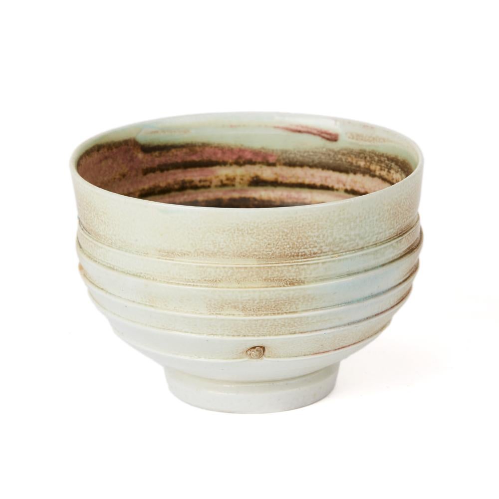 A stylish studio pottery porcelain soda-fired ribbed round shaped bowl standing on a narrow rounded foot by Jack Doherty. The bowl has an indented pattern within the ribbing and is decorated in fired 'rust' elements with similar coloring along with