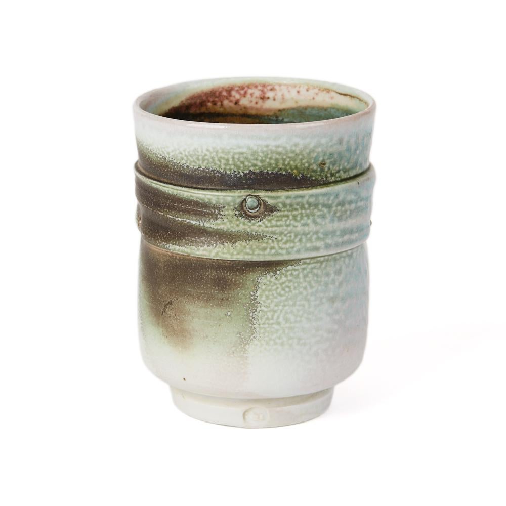 A stylish Studio Pottery porcelain soda-fired ribbed vessel of beaker shape standing on a narrow rounded foot by Jack Doherty. The vessel has an indented pattern within the ribbing and is decorated in turquoise green with fired 'rust' elements with