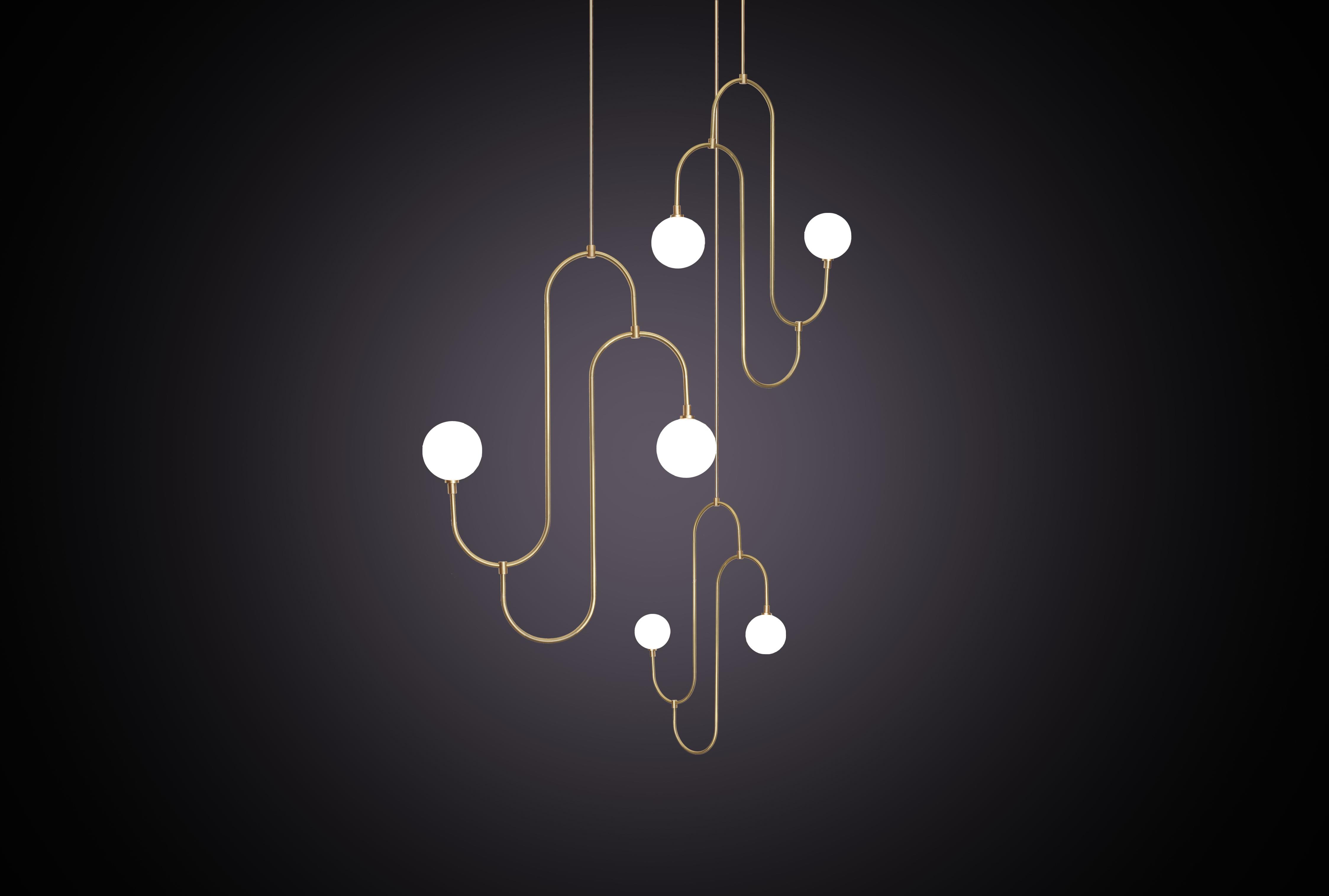 Si ispira ai motivi ripetuti e alla forma scultorea dei gioielli degli anni Trenta. Il pendente incorpora bracci in ottone piegati a mano che sostengono il vetro di cristallo bianco perlato, creando un elemento di illuminazione decorativo e