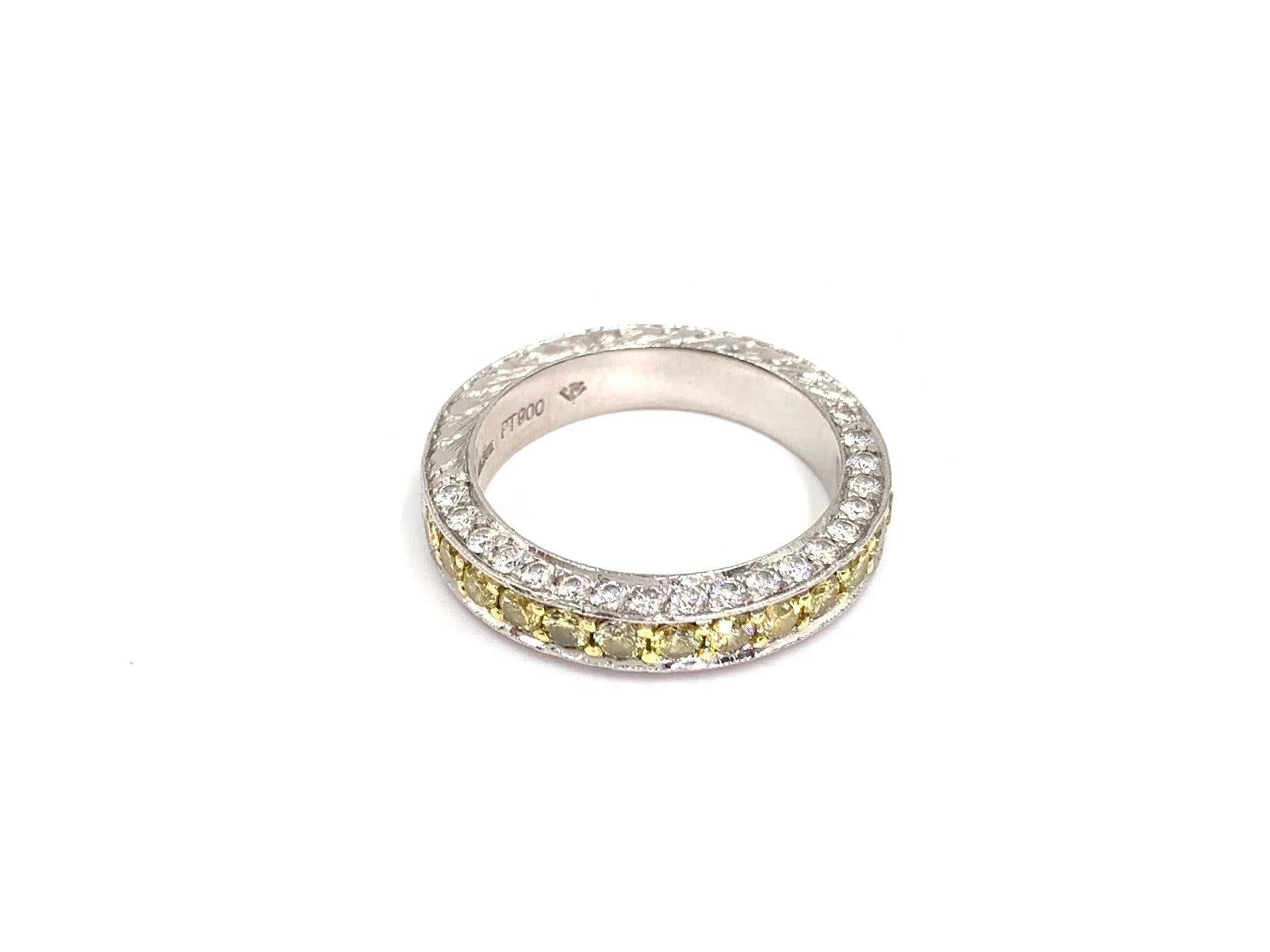 Made with superior quality by expert jeweler Jack Kelége, this beautiful detailed solid platinum wedding band features a center row of  15 fancy yellow diamonds flanked by two rows of white diamonds on the side profile. Yellow diamond total weight