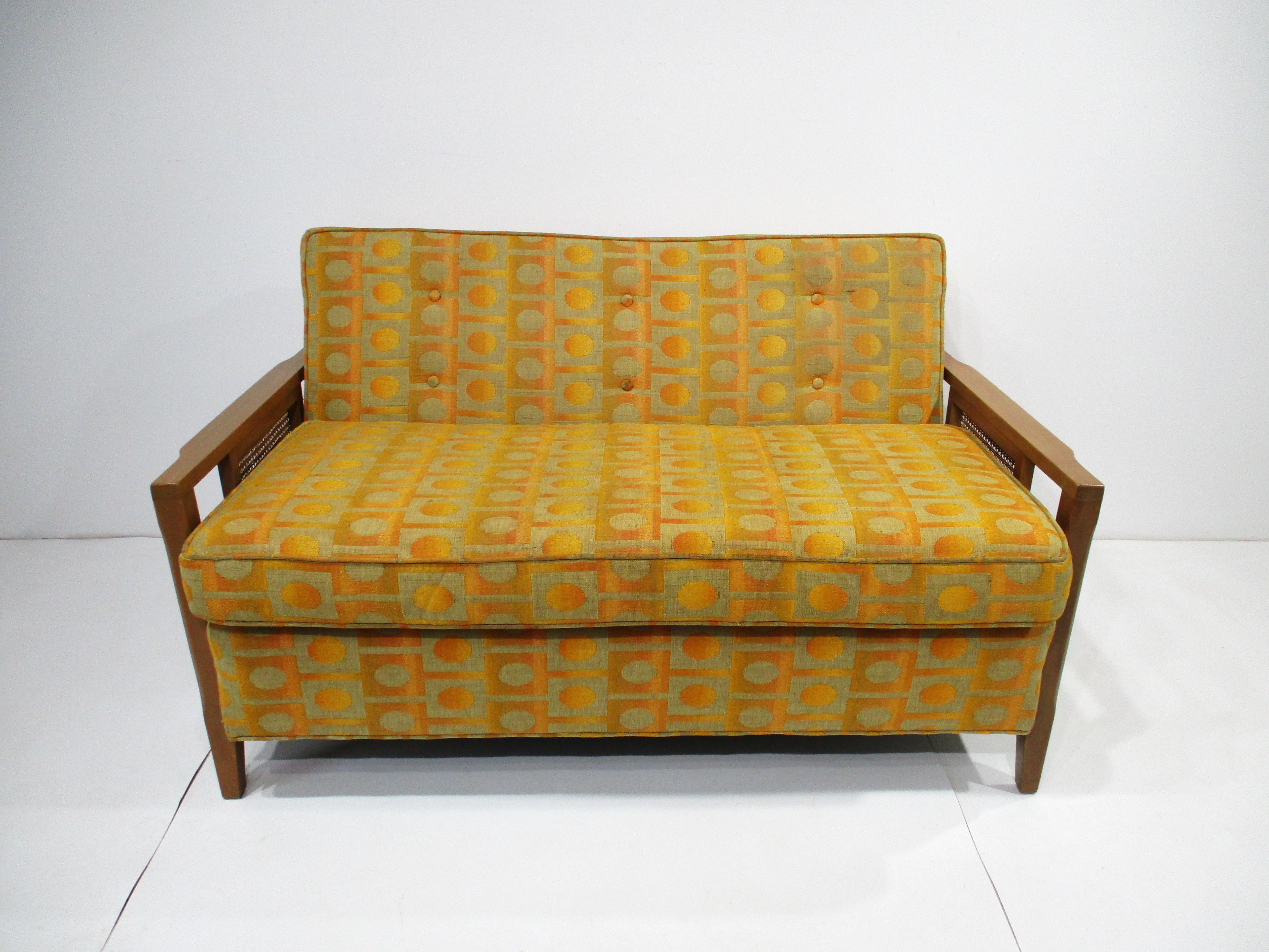 Un loveseat de mediados de siglo tapizado en una tela de estilo Jack Lenor Larsen conocida por sus diseños y colores únicos. Este loveseat de buena factura se fabricó a la manera de la empresa de muebles Henredon, con brazos de madera y paneles