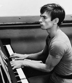 Rudolf Nureyev photographed playing the piano during a rehearsal break