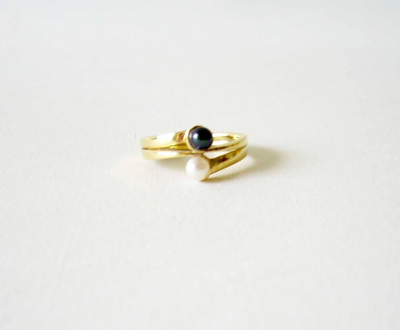 Dainty 14k gold ring featuring one white and one black pearl at center, created by Jack Nutting of San Francisco, California circa 1970's.  Ring is a finger size 5.5 to 5.75 and is unsigned.  From the estate of the artist, Jack Nutting.  In very