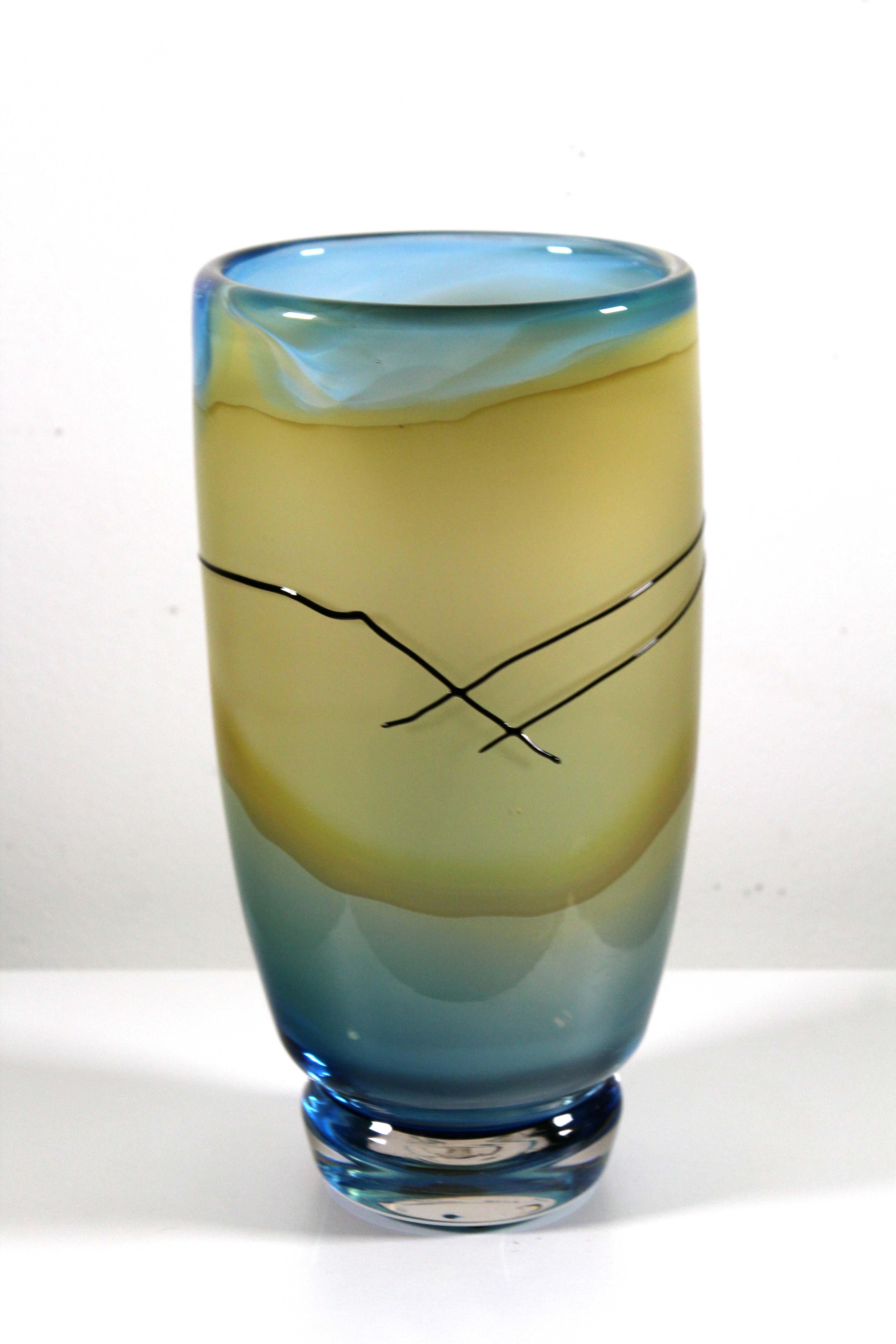 Un vase postmoderne en verre soufflé à la bouche par Jack Schmidt. Signature gravée sur le bas et datée de 1986. Le vase présente une palette de couleurs sereines, jaune doré et bleu aqua, et l'artiste a ajouté une ligne noire stylisée et audacieuse