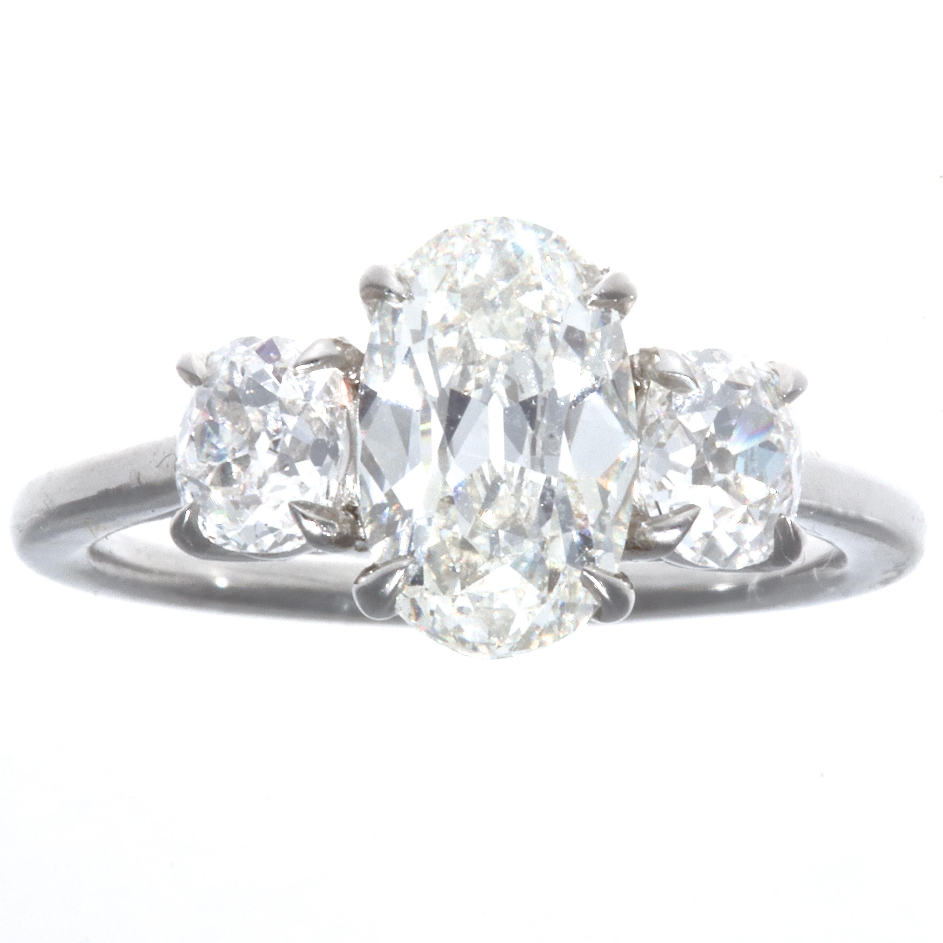 Hard to believe the center stone weighs only 1.64 carats. The oval brilliant cut is unique and full of life. GIA certified J color, VVS1 clarity.  Accented by two old mine cut diamonds weighing  approximately  0.70 carats, G-H color SI clarity. The
