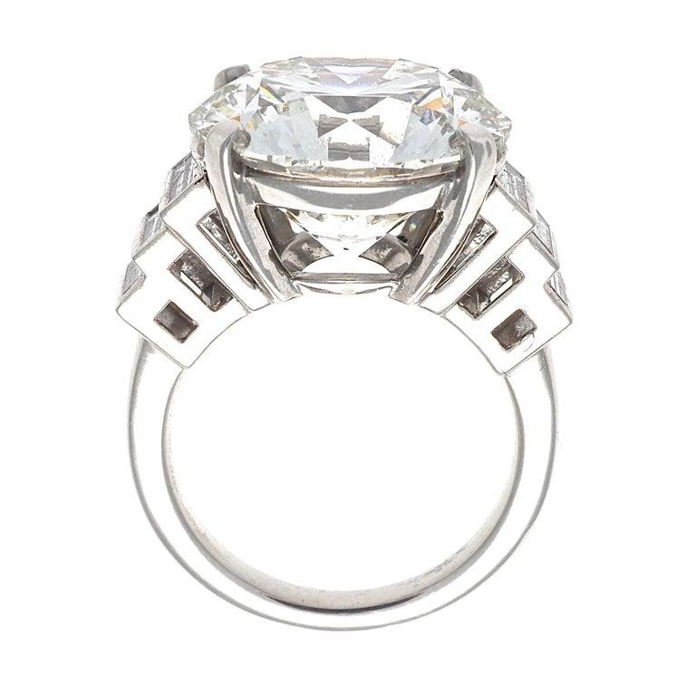 Featuring a 12.23 carat round brilliant cut diamond that is GIA certified as J color, VS2 clarity, triple X. Excellently cut to perfection for maximum beauty and sparkle. Set among descending near colorless baguette cut diamonds. Crafted in