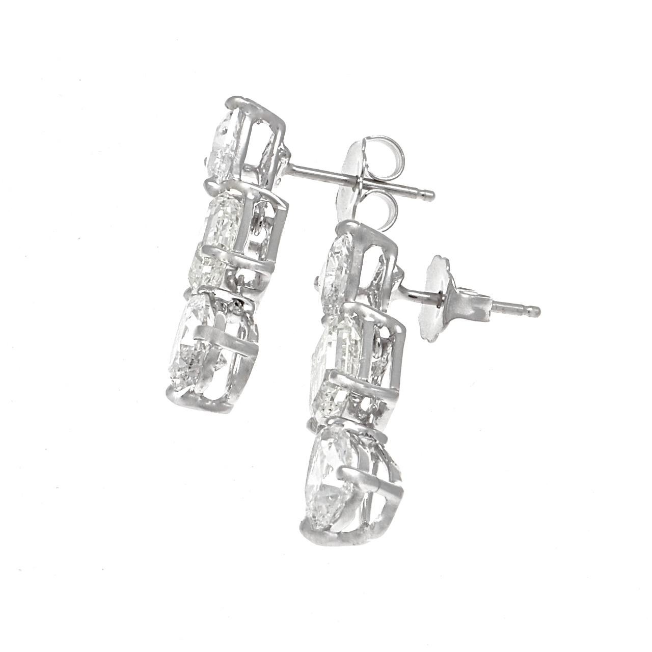 A configuration of abstract shapes aligning into stylish fashion. Featuring approximately two 0.50 carat trillion cut diamonds suspending two GIA certified 1.01 carat emerald cut diamonds dangling two GIA certified pear shaped diamonds weighing 0.76