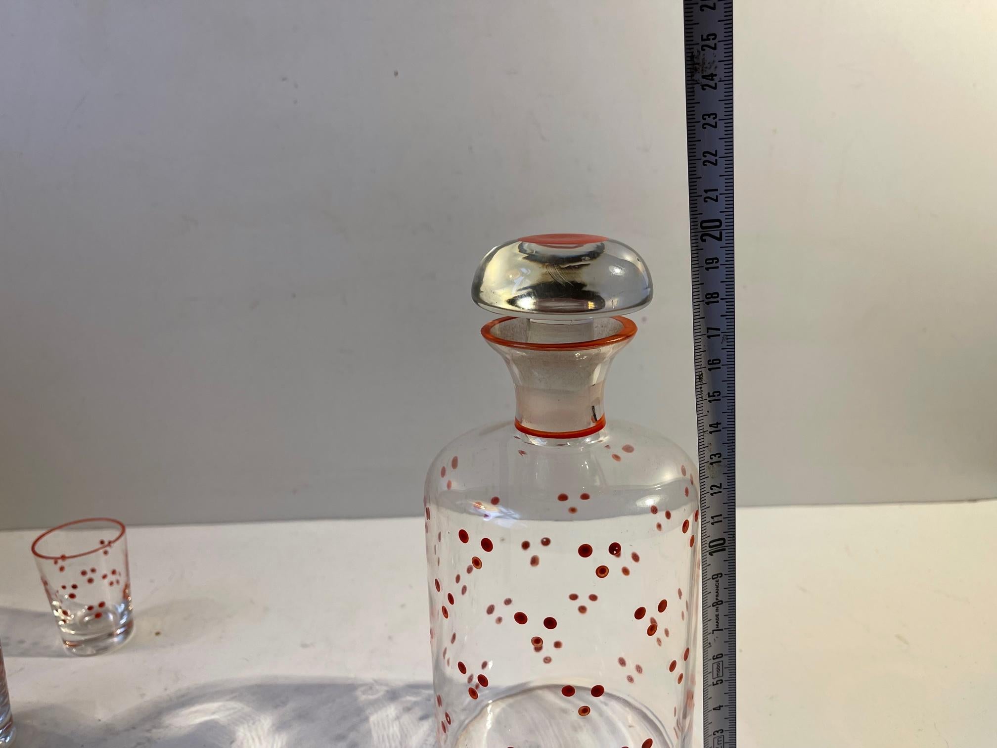 Decanter set catalogued as 'No Name' in the Holmegaard Catalogue from 1937. It was designed by Jacob Eiler Bang and features enamel dots applied by hand. The decanter is accompanied by 3 matching shot glasses. The fourth glass that will come along