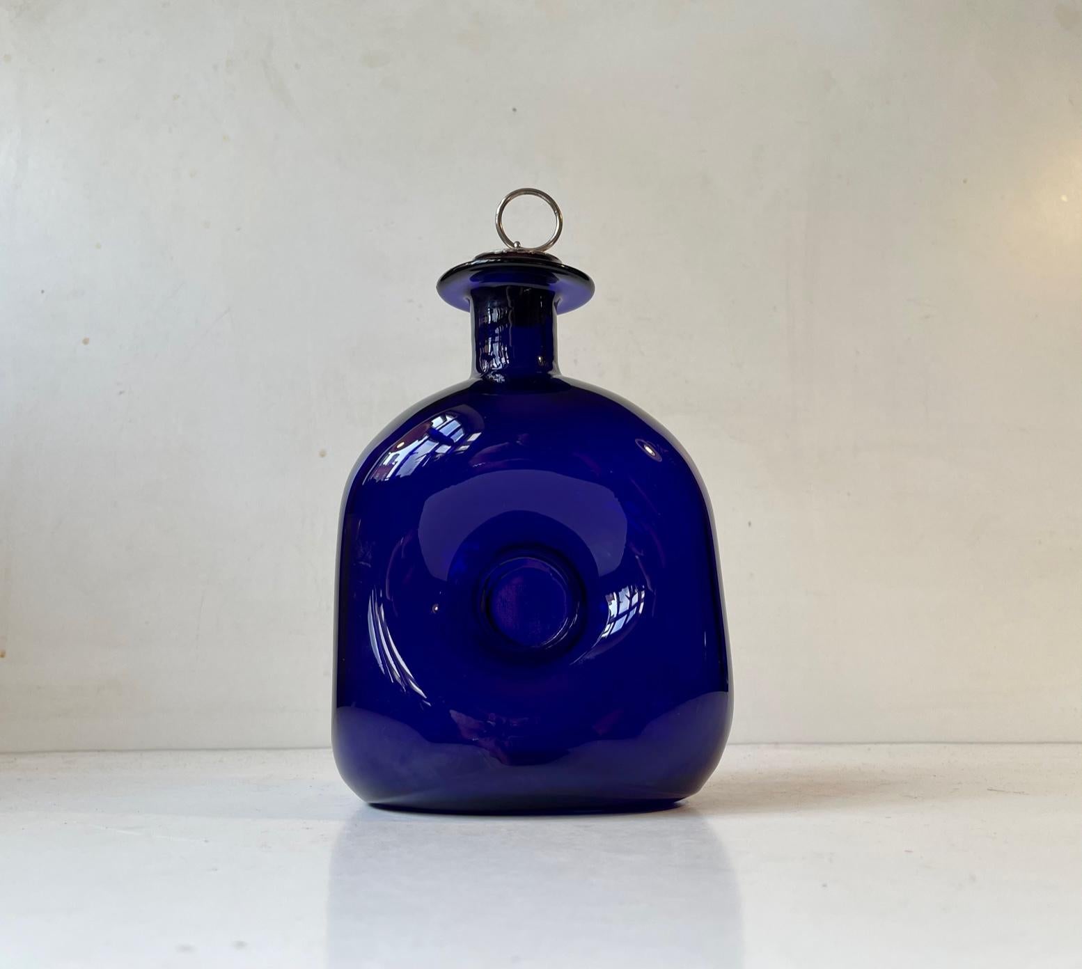 Hand-blown decanter catalogued as 'No Name' in the Holmegaard Catalogue from 1963. Its commonly referred to as 'squeeze' decanter and it was designed by Jacob Eiler Bang. It is rare in cobalt blue. In was made at Holmegaard Kastrup Glasværk from