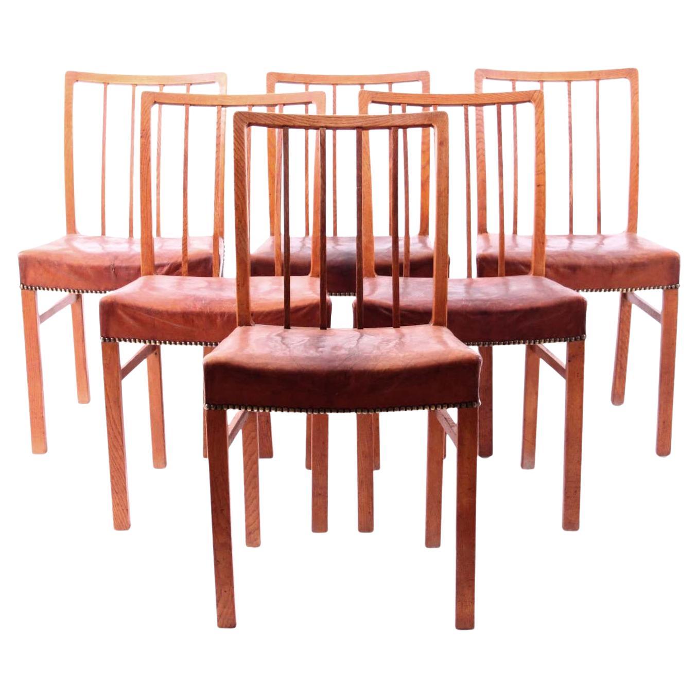 Set of 6 Oak chairs with original patinated Niger leather.

Jacob Kjær (1896–1957) was a Danish furniture designer and cabinetmaker.
Kjær received training as a cabinetmaker in the workshop of his father who was also a furniture maker. After