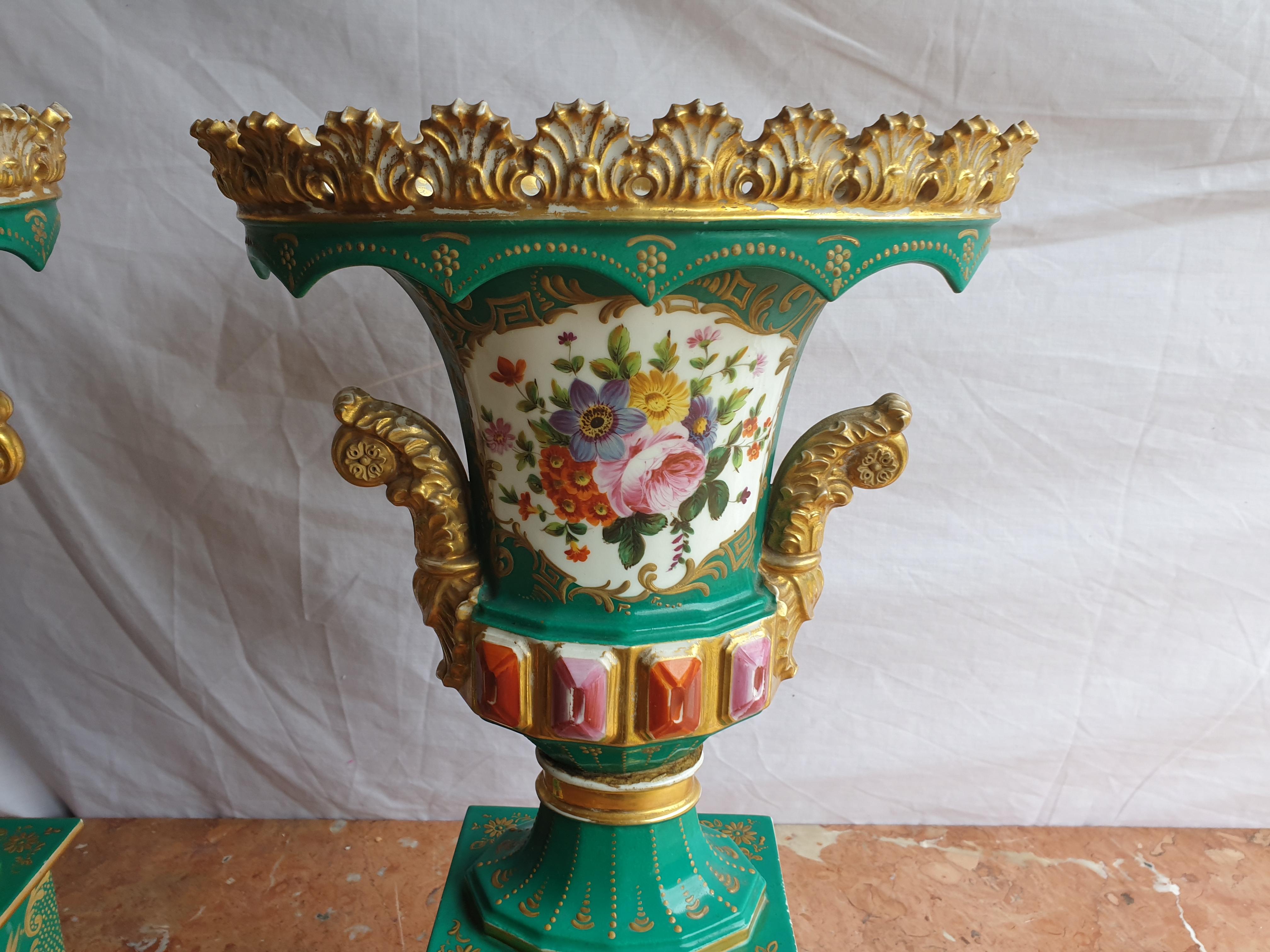 An extremely impressive pair of Jacob Petit hand painted emerald green vases finished with 24k gold gilt fine detailing. On one side of the vase it depicts a hand painted panel with an assortment of summer flowers and on the other side a finely