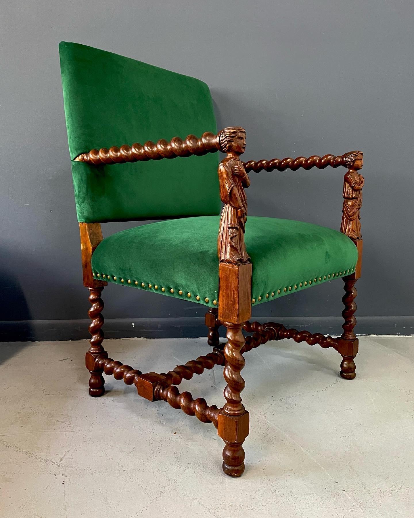 Wonderfully regal armchair constructed of oak with a barley twist design and two carved figures on the arm front. This chair has been carefully restored and reupholstered with a brilliant emerald green velvet.